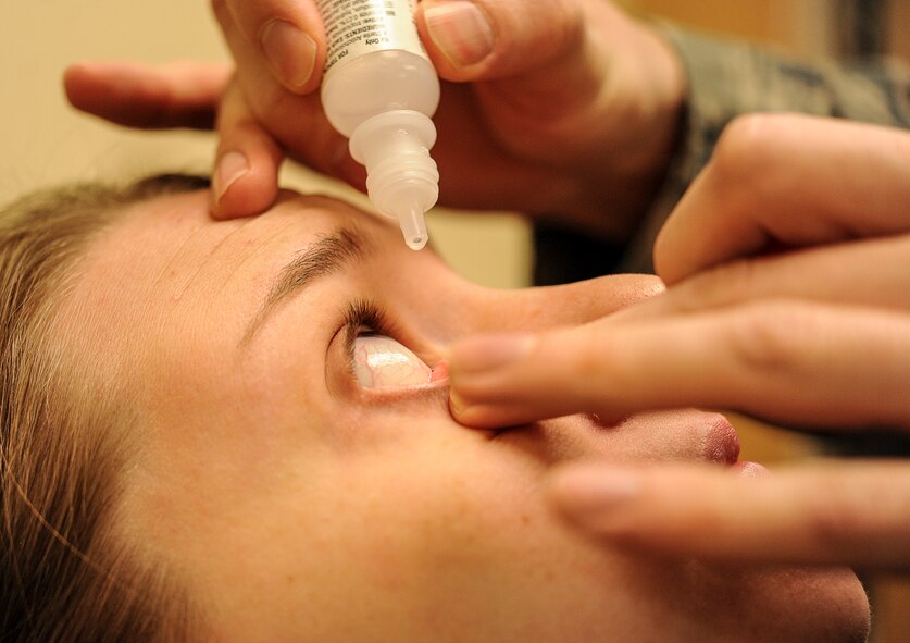 Chelsea Hanson leans back as Capt. Makay Neilson, 5th Medical Operations Squadron optometrist, administers eye drops on Minot Air Force Base, N.D., March 23, 2015. The eye drops are used to dilate a patient’s pupils so that the optometrist can have a better view of the inside of the eye during examination. (U.S. Air Force photo/Senior Airman Stephanie Morris)