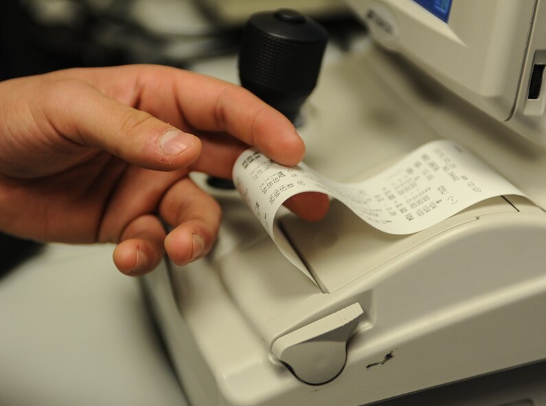 A slip of paper containing prescription information prints from an auto refractor in the optometry clinic on Minot Air Force Base, N.D., March 23, 2015. The refractor provides an objective measurement of a person’s refractive error by measuring how light is changed when it enters the eye. (U.S. Air Force photo/Senior Airman Stephanie Morris)