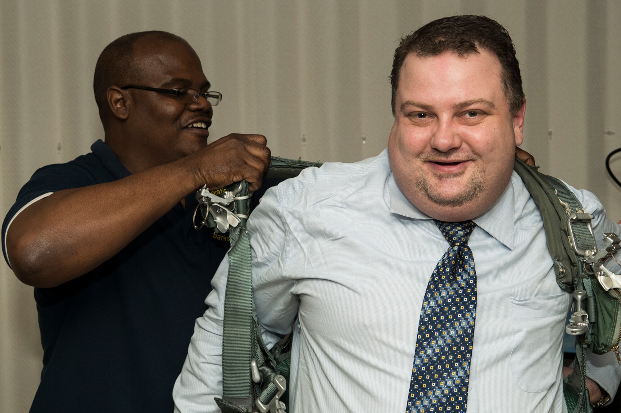 Mr. Carl Whitaker of the 307th Operational Support Squadron helps Mr. Bob Vincent, the Communication Director for the Fort Worth Airpower Foundation, into parachute rigging so he can experience the virtual parachute trainer on Barksdale Air Force Base, La. on March 19, 2015. The council received a tour of Barksdale Air Force Base while they visited the 307th Bomb Wing. (U.S. Air Force Photo by Master Sgt. Greg Steele/Released)