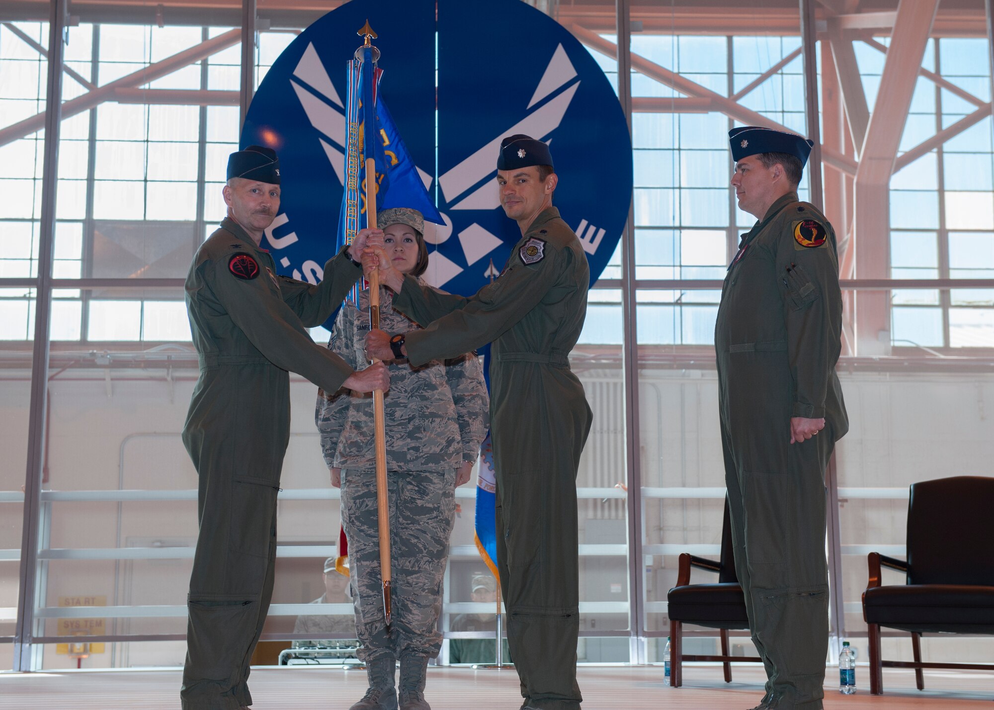 Lieutenant  Colonel  Marshall Chalverus, 54th Operations Support Squadron outgoing commander, passes the 54th OSS guidon to Col. Jeff Jensen, 54th Fighter Group commander, symbolizing stepping down from commanding the squadron during the 54th OSS change of command at Holloman Air Force Base, N.M., March 27, 2015. In the ceremony, Lt. Col. Jerod Rick assumed command of the 54th OSS from Lt. Col. Marshall Chalverus. The 54th OSS is a fighter training unit that trains 45 percent of all F-16 Falcon student pilots. They also manage Intelligence, Air Crew Flight Equipment, and Simulator and Training Devices. (U.S. Air Force photo by Airman 1st Class Emily Kenney / Released)