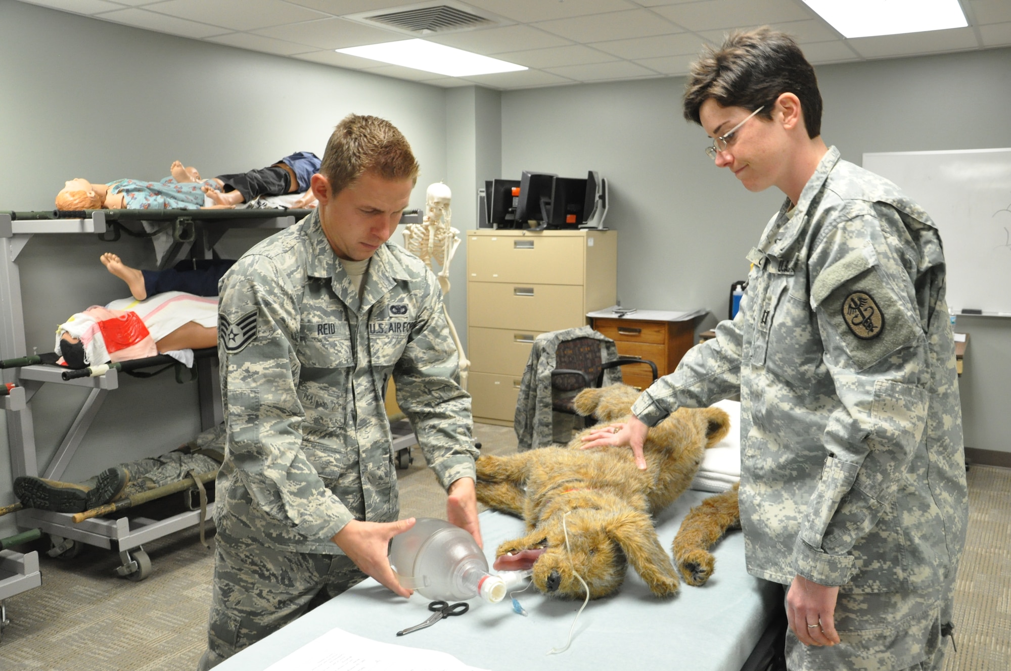 During simulated training for military working dog handlers at Wright-Patterson Medical Center March 23, Staff Sgt. Joshua Reid (left) has cleared the airway and is administering air to a dog mannequin. Capt. Sarah Cudd is supervising the procedure and makes sure the mannequin's stomach inflates and deflates properly while Reid completes the procedure. (Air Force photo by Kimberly Gaither) 