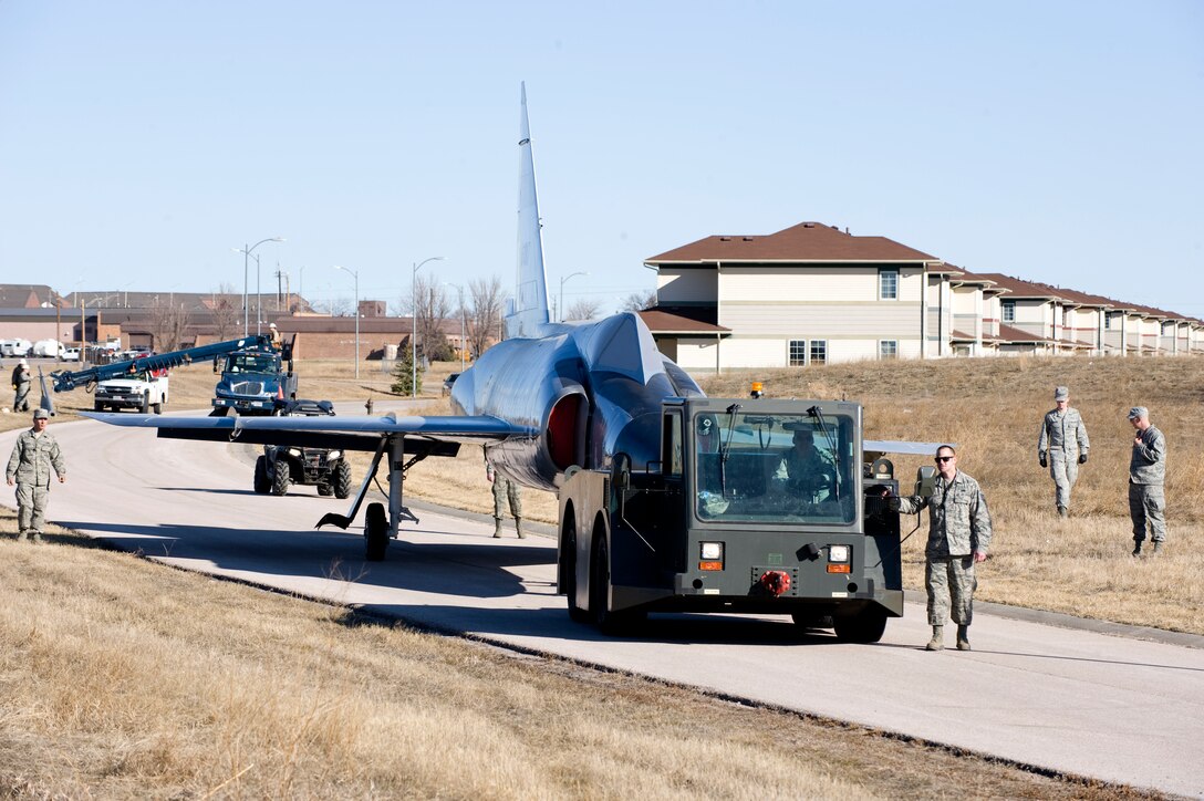 Various units from the 28th Bomb Wing transport an F-102 Delta Dagger through base housing to the South Dakota Air and Space Museum at Ellsworth Air Force Base, S.D., March 13, 2015. The F-102 is an aircraft that first flew in April 1956 to combat the long range, nuclear-capable bombers of the Soviet Union, serving as a deterrent for enemy aircraft. It flew for more than 20 years prior to its retirement in 1976. (U.S. Air Force photo by Senior Airman Hailey R. Staker/Released)
