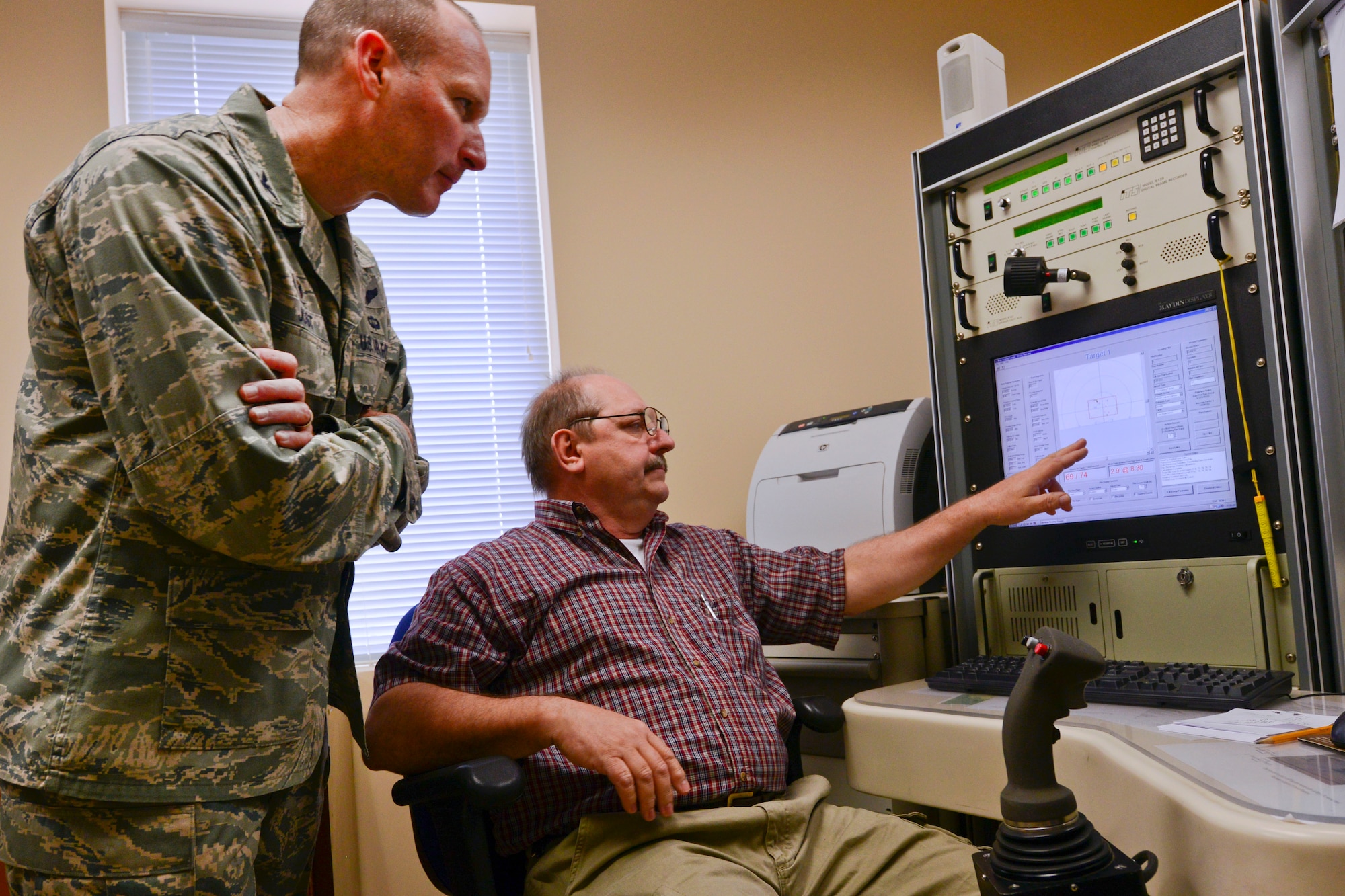 George Nash, Poinsett Electronic Combat Range computer operator, shows U.S. Air Force Col. Stephen Jost, 20th Fighter Wing commander, the weapons impact scoring system as bullets hit the target at Poinsett Electronic Combat Range, Sumter, S.C., March 5, 2015. The WISS scores targets hit by military members as they fly their aircraft over the training range. (U.S. Air Force photo by Senior Airman Tabatha Zarrella/Released)