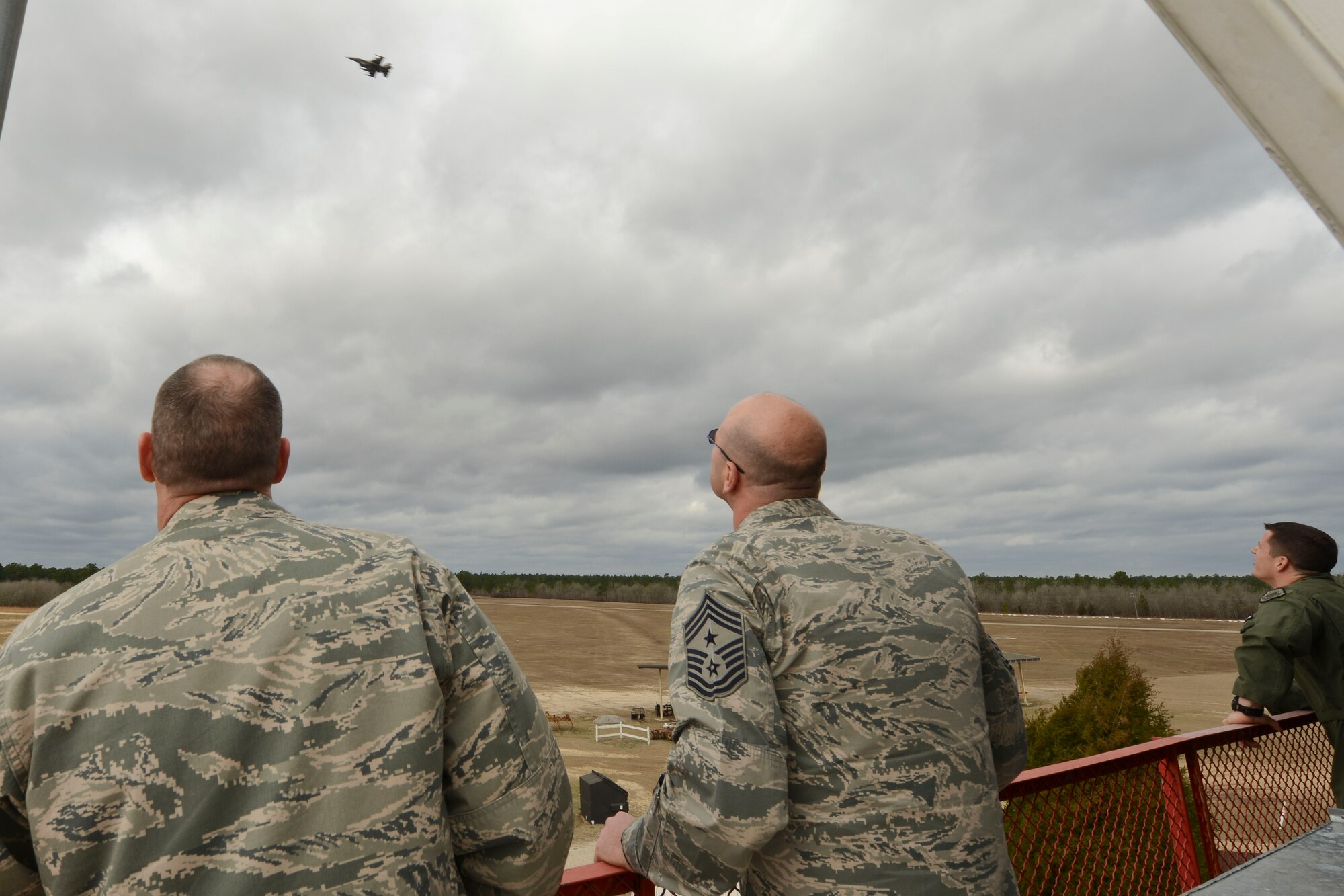 U.S. Air Force Col. Stephen Jost, 20th Fighter Wing commander, and Chief Master Sgt. Charles Mills, 20th FW command chief, watch as an F-16CM Fighting Falcon flies over Poinsett Electronic Combat Range, Sumter, S.C., Mar. 5, 2015. Jost and Mills went out to Poinsett as part of the “Behind the Scenes” series, getting to know more informatio about each job and the Airmen and people who help accomplish Shaw AFB missions. (U.S. Air Force photo by Senior Airman Tabatha Zarrella/Released)
