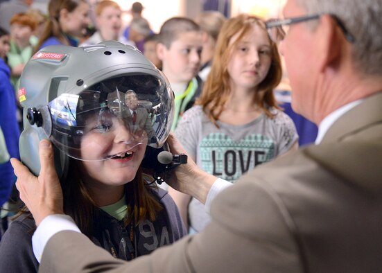 Steve Tourangeau, BAE Systems advocate, assists Elise Rice as she tries on their Striker helmet designed for fighter pilots. (U.S. Air Force photo by Tommie Horton)
