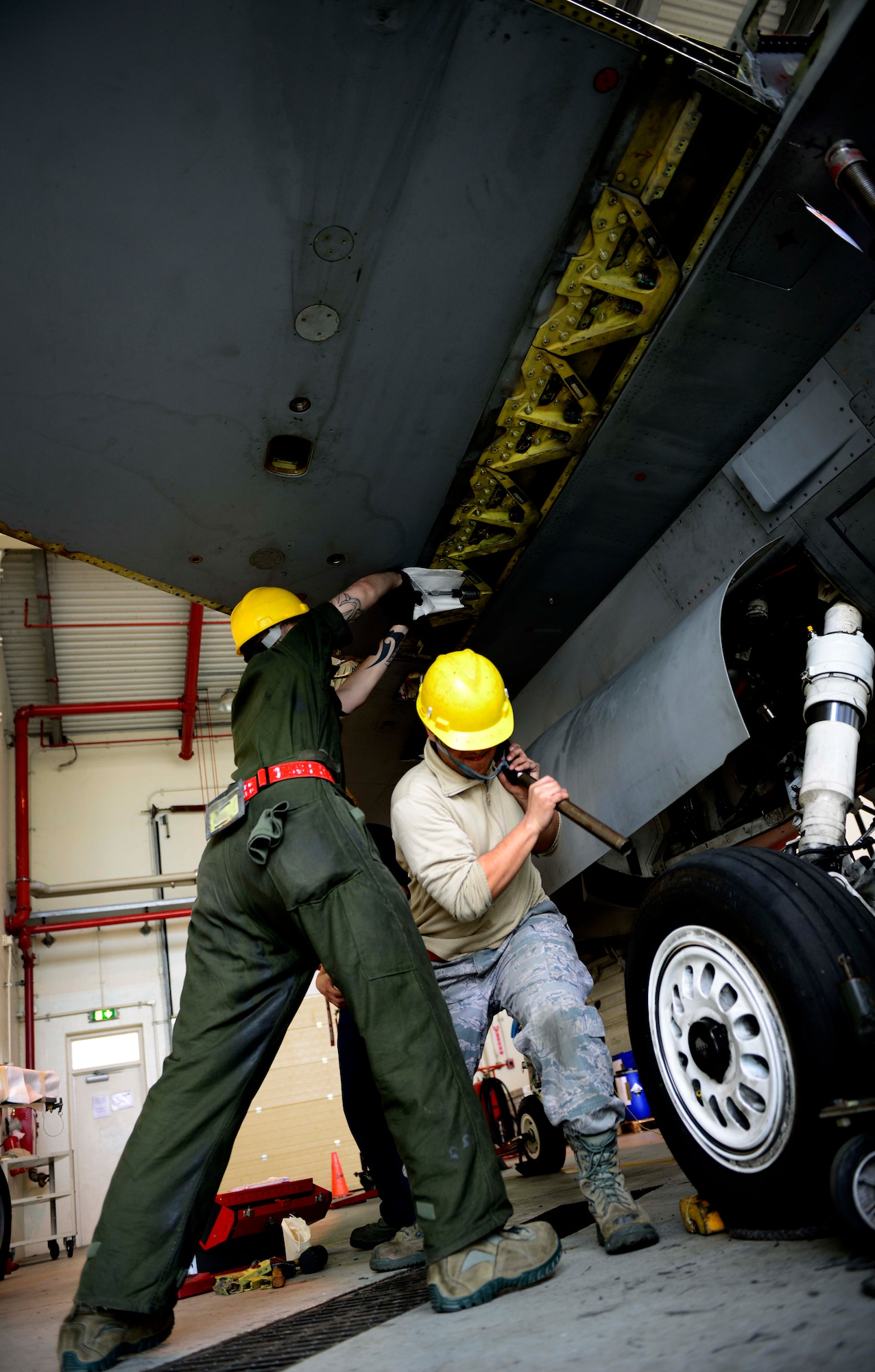 (From left) U.S. Air Force Senior Airman Jonathan Tolson and Staff Sgt. Daniel Caba, 31st Maintenance Squadron aircraft fuel systems technicians, loosen bolts of an F-16 Fighting Falcon before removing its wing, March 25, 2015 at Aviano Air Base, Italy. The wing will be transported to Hill Air Force Base, Utah, where it will be overhauled and refurbished. (U.S. Air Force photo by Senior Airman Areca T. Wilson/Released)
