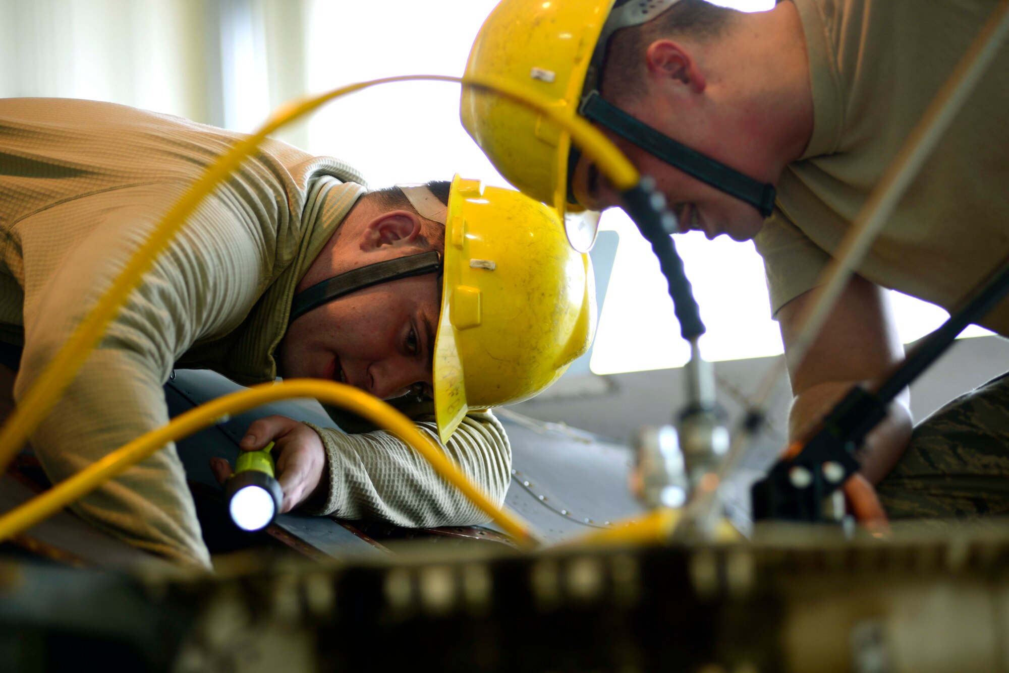 (From left) U.S. Air Force Airman 1st Class Edward Hoskins and Staff Sgt. Dale Marsh, 31st Maintenance Squadron aircraft fuel systems repair technicians, loosen parts of an F-16 Fighting Falcon before removing its wing, March 25, 2015 at Aviano Air Base, Italy. The old wing will be replaced with a new one valued at $750,000. (U.S. Air Force photo by Senior Airman Areca T. Wilson/Released)