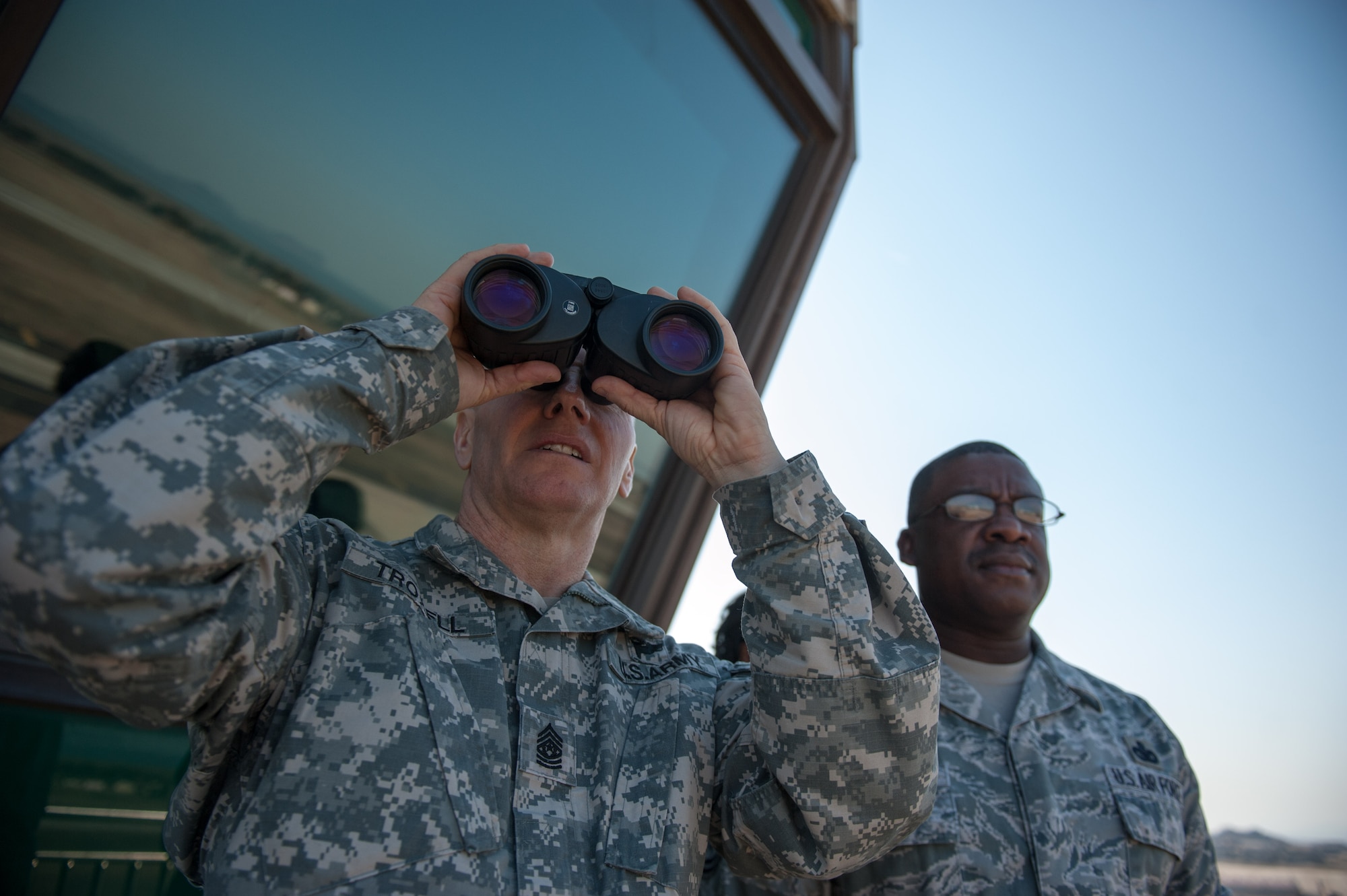 Army Sgt. Maj. John Troxell, U.S. Forces Korea Command Sgt. Maj., and Chief Master Sgt. Lee Barr, 8th Fighter Wing command chief, look onto the runway during a tour to the air traffic control tower at Kunsan Air Base, Republic of Korea, March 24, 2015. During Troxell’s visit, Troxell saw how the Wolf Pack contributes to deterring aggression on the Korean Peninsula and remain ready to fight tonight. (U.S. Air Force photo by Senior Airman Taylor Curry/Released)