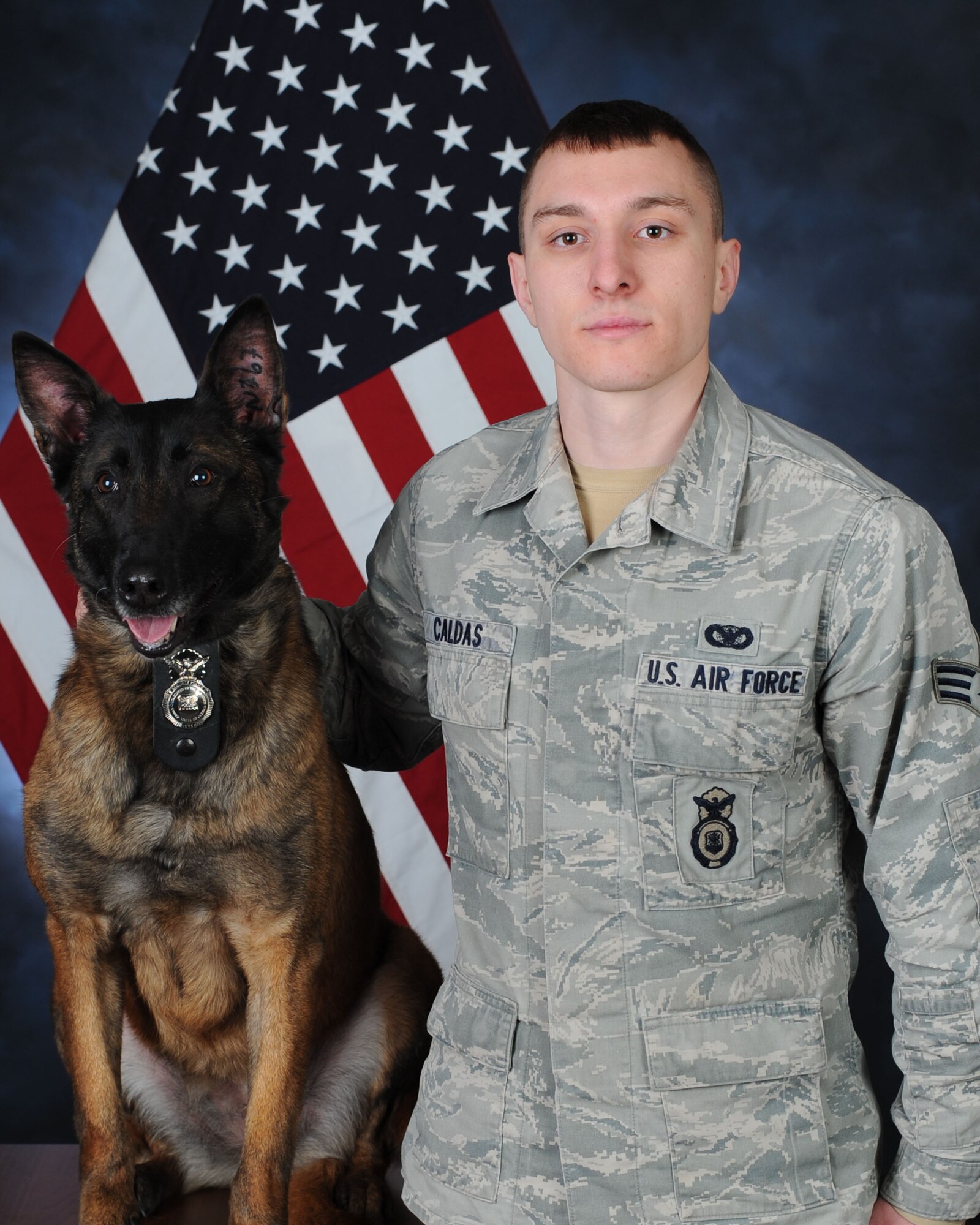 U.S. Air Force Senior Airman Daniel Caldas, 100th Security Forces Squadron Military Working Dog handler from Milford, Mass., and MWD Vvonya pose for an official photograph March 12, 2015, on RAF Mildenhall, England. The dogs are used as patrol, to find any suspicious activity or unattended packages and if not working the roads, the handler will be doing training with his dog to keep the dogs proficient at what they do. (U.S. Air Force photo by Senior Airman Christine Griffiths/Released)