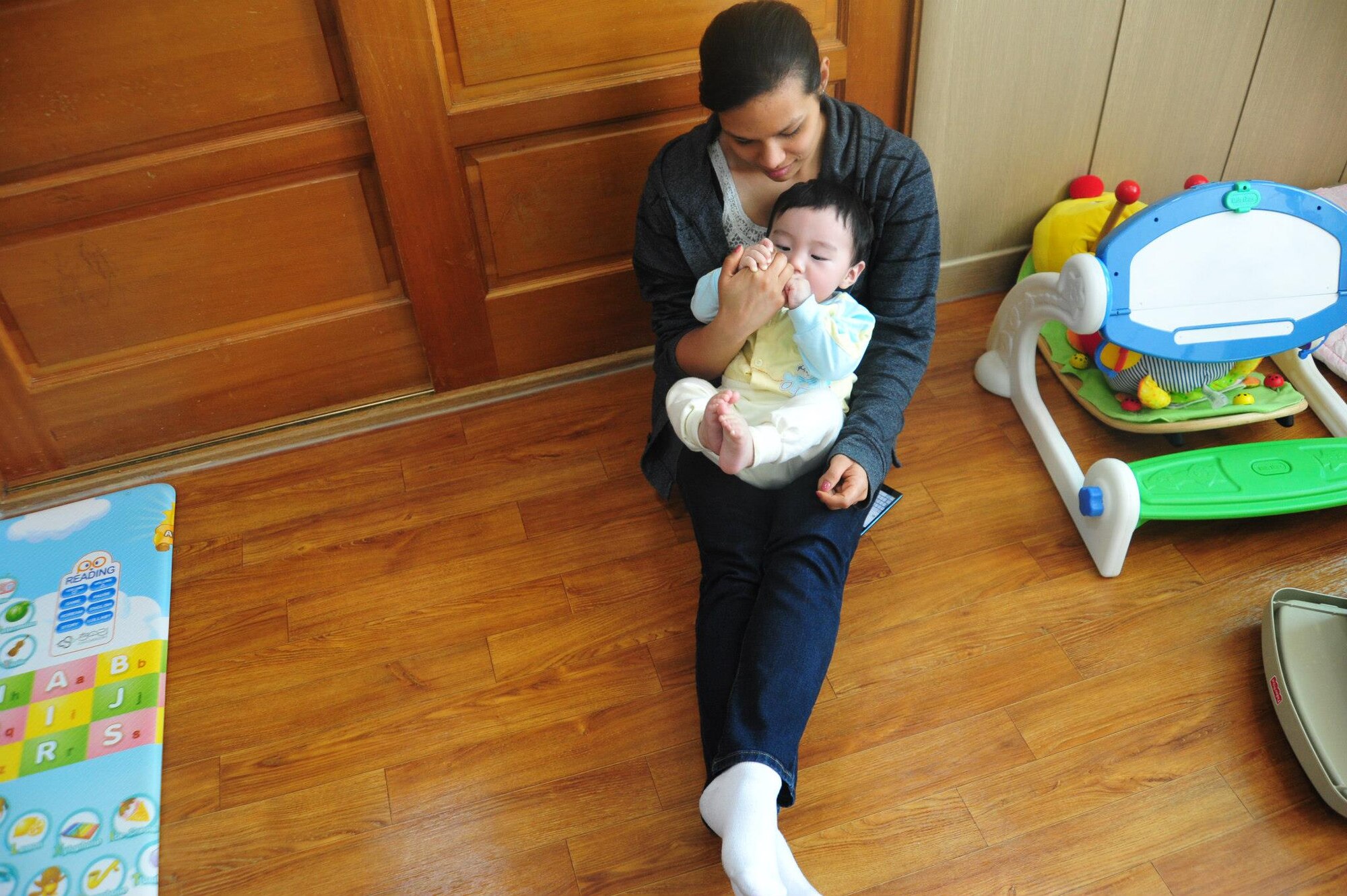 An Airman from the 8th Fighter Wing cuddles with an infant at the Moses Infant Home in Gunsan City, Republic of Korea, March 21, 2015. Thirty-five Airmen from the 8th Fighter Wing and the deployed 120th Expeditionary Aircraft Maintenance Unit volunteered at the home to spend time with the children living there. (U.S. Air Force photo by Capt. Reba Good/Released)