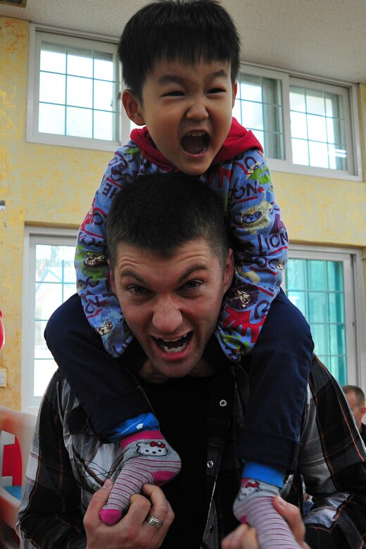 An Airman from the 120th Expeditionary Aircraft Maintenance Unit plays with a toddler at the Moses Infant Home in Gunsan City, Republic of Korea, March 21, 2015. Thirty-five Airmen from the 8th Fighter Wing and the deployed 120th Expeditionary Aircraft Maintenance Unit volunteered at the home to spend time with the children living there. (U.S. Air Force photo by Capt. Reba Good/Released)