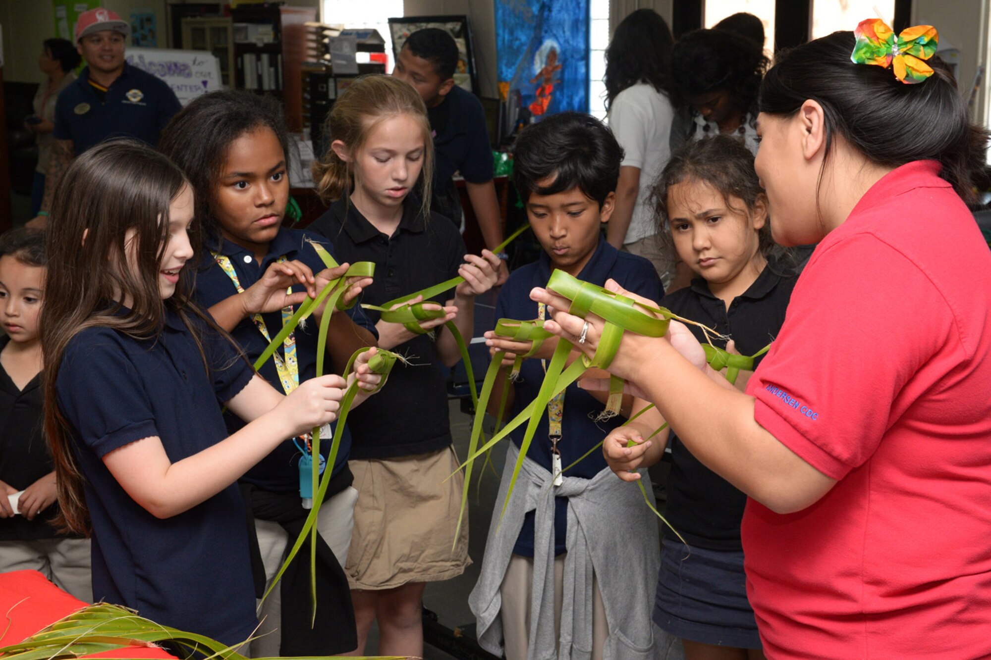 Noreen Castro, 36th Force Support Squadron administration clerk, teaches Team Andersen children how to weave palm leaves during a Chamorro Month presentation March 26, 2015, at Andersen Air Force Base, Guam. The 36th FSS hosted activities for Team Andersen children to learn about the Chamorro culture. (U.S. Air Force photo by Airman 1st Class Joshua Smoot/Released)