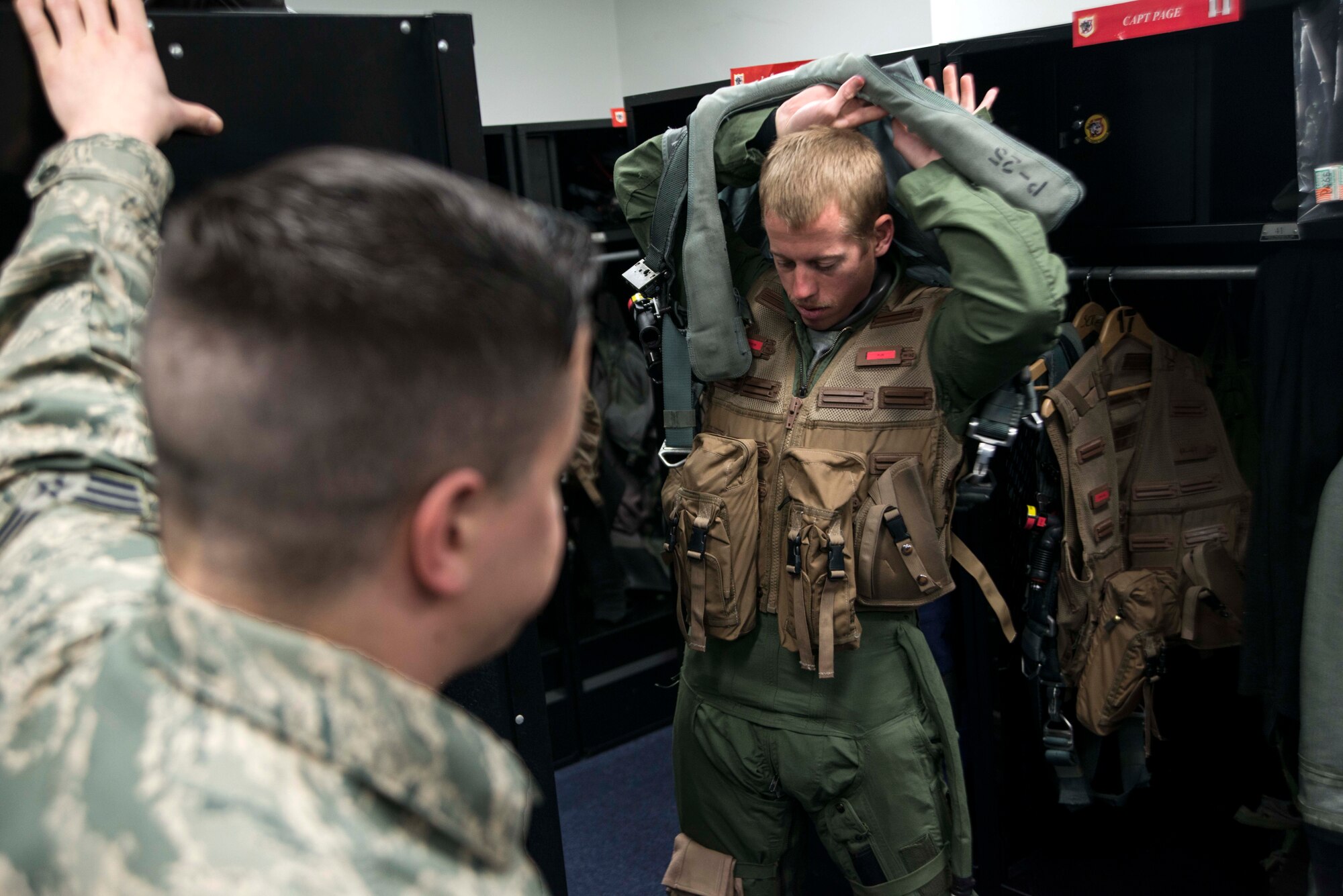 Senior Airman Robert McClung, left, 13th Fighter Squadron aircrew flight equipment technician, talks with Capt. Jeffrey Goode, 13 FS F-16 Fighting Falcon pilot, before a sortie March 26, 2015, at Misawa Air Base, Japan. As an AFE technician, McClung is responsible for preparing each pilot’s flying gear and performing scheduled maintenance to ensure its reliability. (U.S. Air Force photo by Staff Sgt. Derek VanHorn/Released)