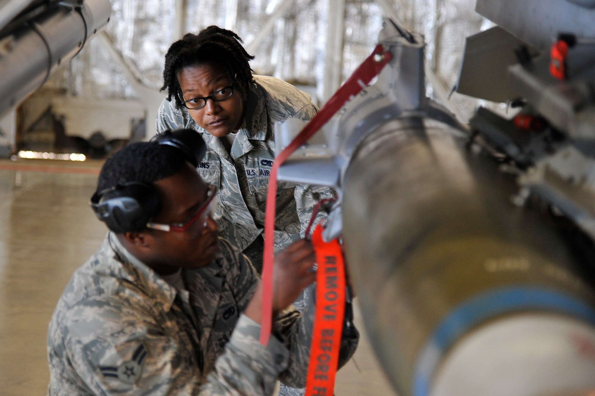 U.S. Air force Senior Airman Kayla Hopkins, 35th Maintenance Group weapons load crew evaluator, inspects an Airman installing an armament onto an F-16 Fighting Falcon at Misawa Air Base, Japan, Mar. 26, 2015. During Hopkins’ evaluation process, she hand-checks for any discrepancies where each armament was loaded. (U.S. Air Force photo by Airman 1st Class Patrick S. Ciccarone/Released)