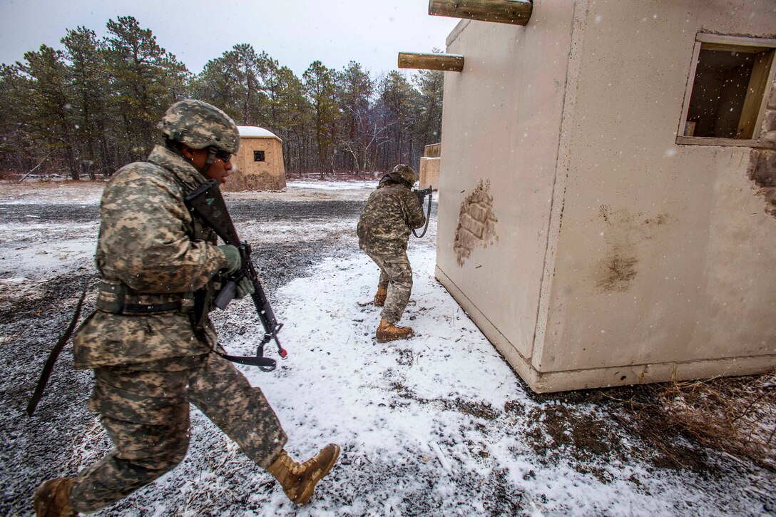 Army Sgt. Wilfredo S. Rodriguez-Ramos, right, provides cover fire as Army Pfc. Emery L. Bowens crosses an open area between buildings at the training site for military operations in urban terrain on Joint Base McGuire-Dix-Lakehurst, N.J., March 20, 2015. Rodriguez-Ramos and Bowens are military police officers assigned to the New Jersey Army National Guard's 328th Military Police Company.