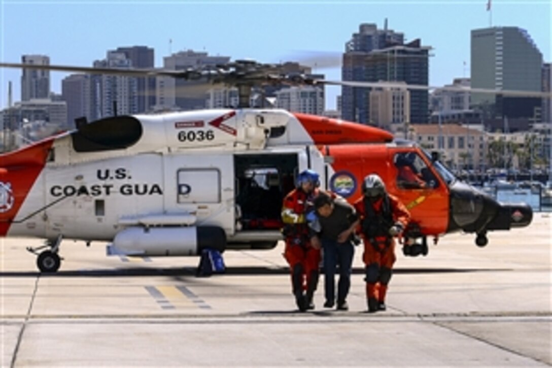 Two Coast Guard flight crewmen help an ailing man get emergency medical services after landing in San Diego, March 26, 2015. The man experienced severe upper abdominal pain aboard a commercial fishing boat about six miles south of San Clemente Island. 
