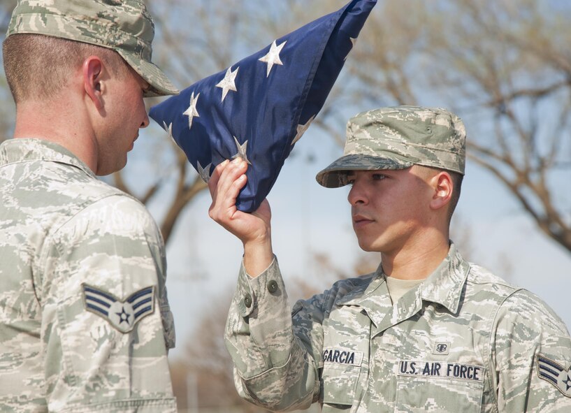 Senior Airman Eric Ruiz Garcia, 71st Medical Support Squadron medical records technician, dresses the national ensign during a retreat ceremony at Vance Air Force Base, Oklahoma, March 23, 2015. The retreat was performed by students from Team Vance's first Airman Leadership School class. (U.S. Air Force photo by Staff Sgt. Nancy Falcon)