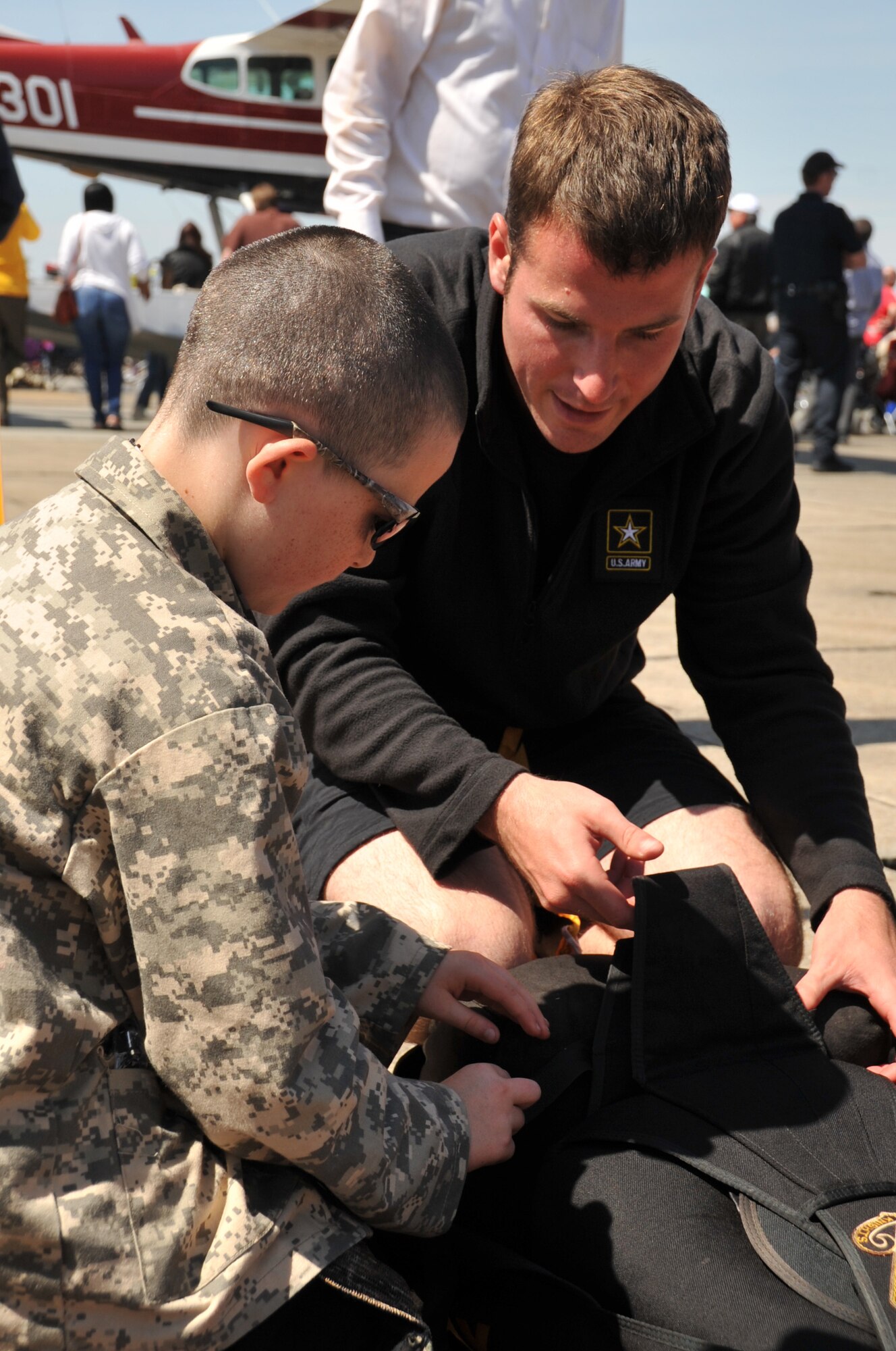 Army Sgt. Travis Downing, a member of the U.S. Army Golden Knights parachute team, shows a visitor of the Keesler Air Force Base "Thunder on the Bay" Air Show and Open House how to pack a chute after conducting a demonstration jump March 28, 2015. (U.S. Air Force photo/Master Sgt. Jessica Kendziorek)