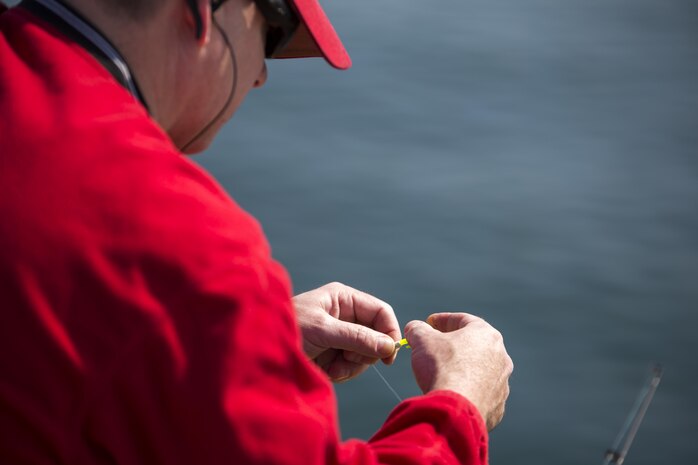 A participant hooks bait to his fishing line at the fishing tournament hosted by Marine Corps Community Services aboard Marine Corps Air Station Iwakuni, Japan, at the station harbor, March 28, 2015. MCCS uses these events to help build camaraderie and offer service members a way to relax. This is the second tournament this year and this time they invited members of the Japan Maritime Self-Defense Force.