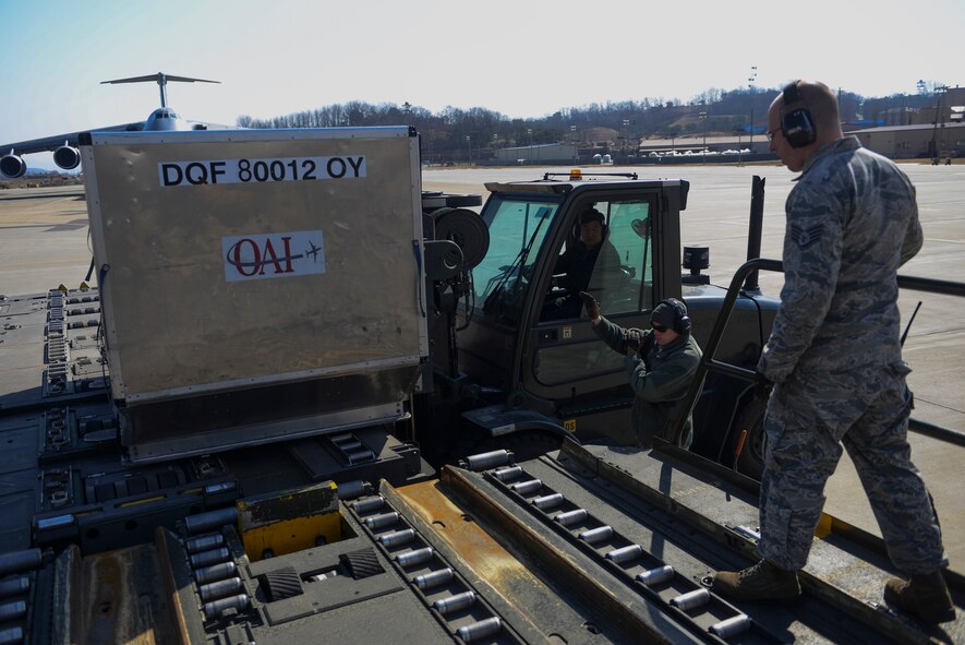 Airman 1st Class Corbin Palmateer, 731st Air Mobility Squadron aircraft service representative, directs the forklift driver while loading the baggage bin onto a pallet spinner March 12, 2015 at Osan Air Base, Republic of Korea. The new process enables the squadron to become more efficient while utilizing their manpower, which might have been required at the aircraft, to perform another mission. (U.S. Air Force photo by Senior Airman David Owsianka)