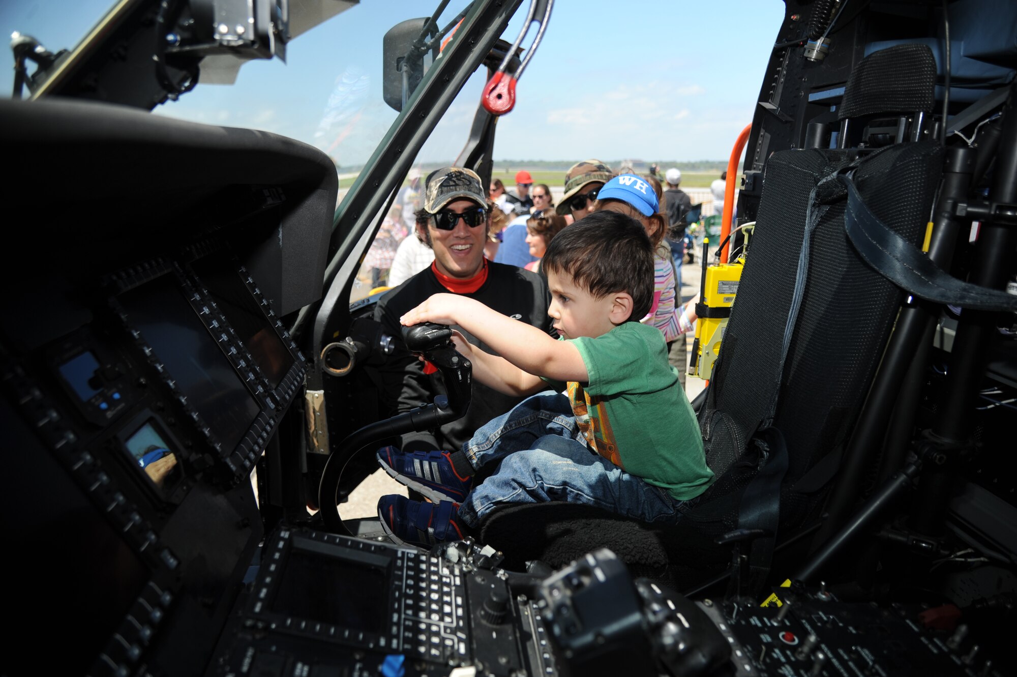 Jeremiah Wright watches his friend’s son, Gideon, as he sits in the cockpit of a coast guard helicopter during Keesler’s Air Show/Open House March 29, 2015, at Keesler Air Force Base, Mississippi.  The event included the U.S. Air Force Thunderbirds and Army Golden Knights along with many other performers, static displays and vendors. (U.S. Air Force photo by Kemberly Groue)