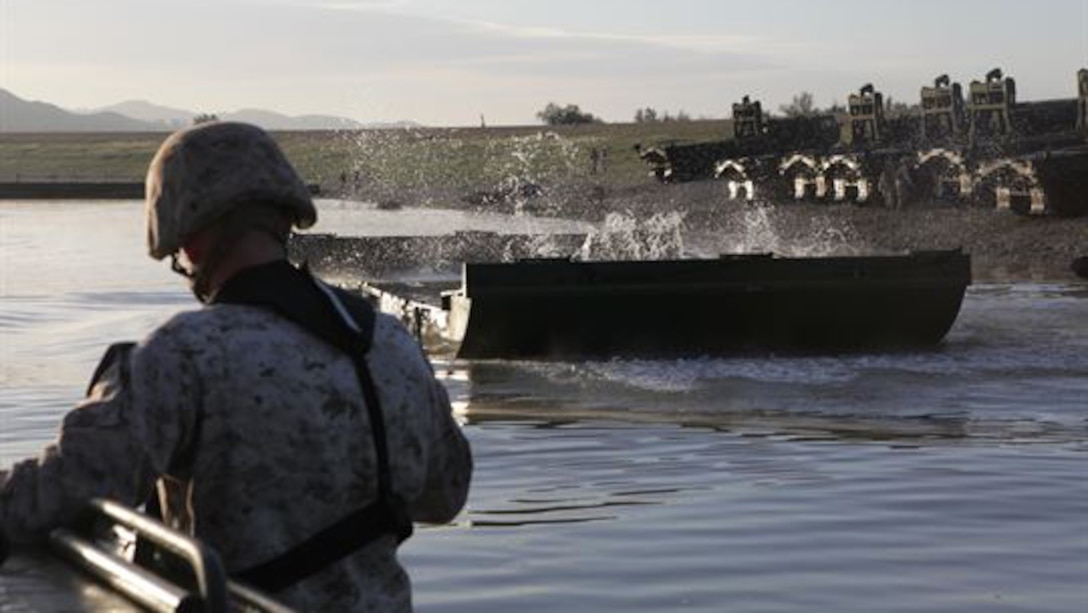 Lance Cpl. Alias A. Wentworth, a deck hand for operations platoon, Bridge Company, 7th Engineer Support Battalion, 1st Marine Logistics Group, awaits a piece of the improved ribbon bridge during an exercise at Lake Elsinore, Calif., March 24, 2015. Marines built an improved ribbon bridge and a medium girder bridge. This event marks the first time a continuous span bridge from shore to shore has been built since 2002.