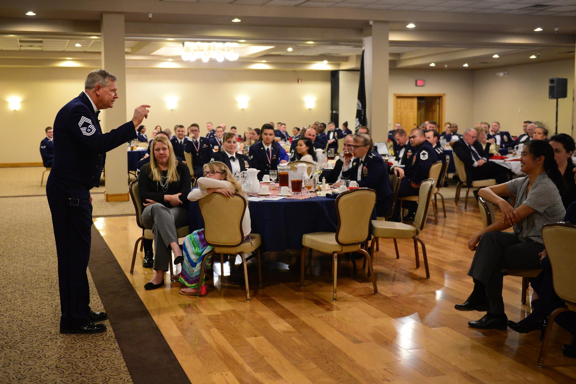 U.S. Air Force retired Chief Master Sgt. John Newhart addresses graduates and their guests at the Airman Leadership School graduation March 26, 2015 at Cannon Air Force Base, N.M. Newhart told stories of his time as a chief at Cannon, emphasizing the qualities of the mentors he employed as a leader. (U.S. Air Force photo/Airman 1st Class Shelby Kay-Fantozzi)  

