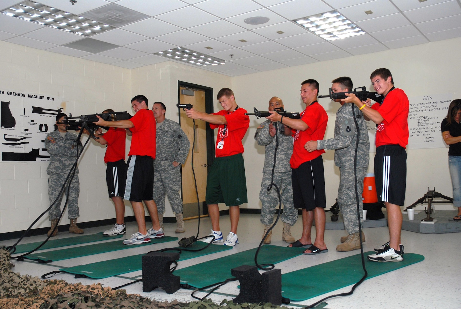 Soldiers from the Florida National Guard's 53rd Infantry Brigade Combat Team's rear detachment assist participants in the NFL's High School Player Development program in operating simulated weapons while touring the Armed Forces Reserve Center in Pinellas Park, Fla. The HSPD and 53rd IBCT rear detachment teamed up to assemble care packages for deployed Florida National Guardsmen, July 9.