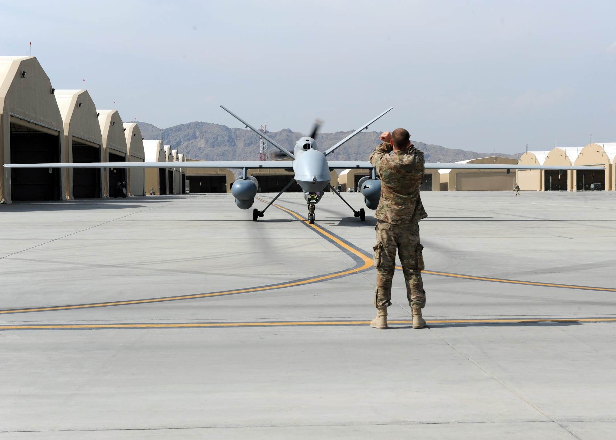 An Airman assigned to the 451st Expeditionary Aircraft Maintenance Squadron marshals an MQ-9 Reaper to the runway prior to launch March 20, 2015, at Kandahar Airfield, Afghanistan. Airmen assigned to the 451st EAMXS provide 24/7 maintenance support to the Air Force’s largest Reaper unit, ensuring ground troops are supported around the clock. (U.S. Air Force photo/Staff Sgt. Whitney Amstutz)