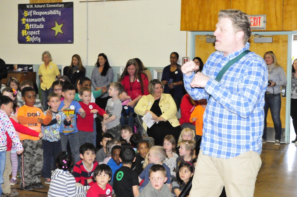 Music teacher Chris Frasu leads students in singing during the March 18 ceremony at Ashurst Elementary School commemorating the school’s 50th anniversary and upcoming closing.