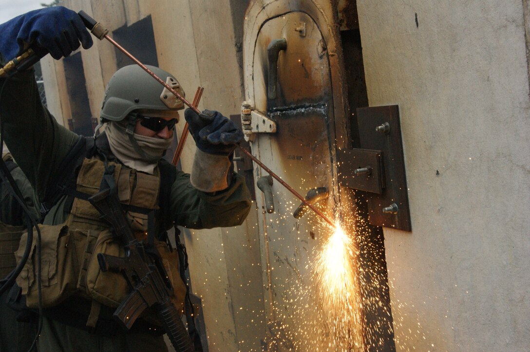 Marine students at the Methods of Entry School use a torch to breach a steel hatch during an exercise at the Goettge Demolition Range.