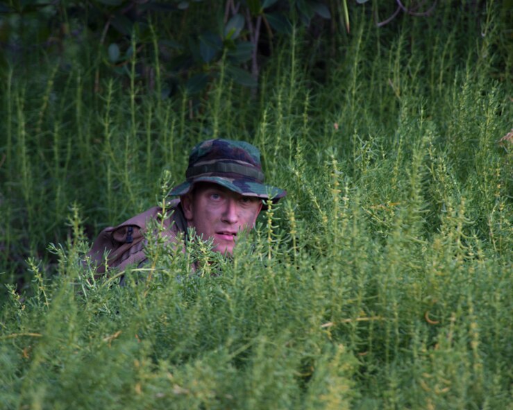Capt. Matt Savage, a pilot for the 96th Air Refueling Squadron, looks out for opposition forces during combat survival training on Joint Base Pearl Harbor-Hickam, Hawaii, March 26, 2015. The aircrew uses teamwork to conceal their location, evade opposition forces, and practice proper recovery procedures. (U.S. Air Force photo by Tech. Sgt. Aaron Oelrich/Released)