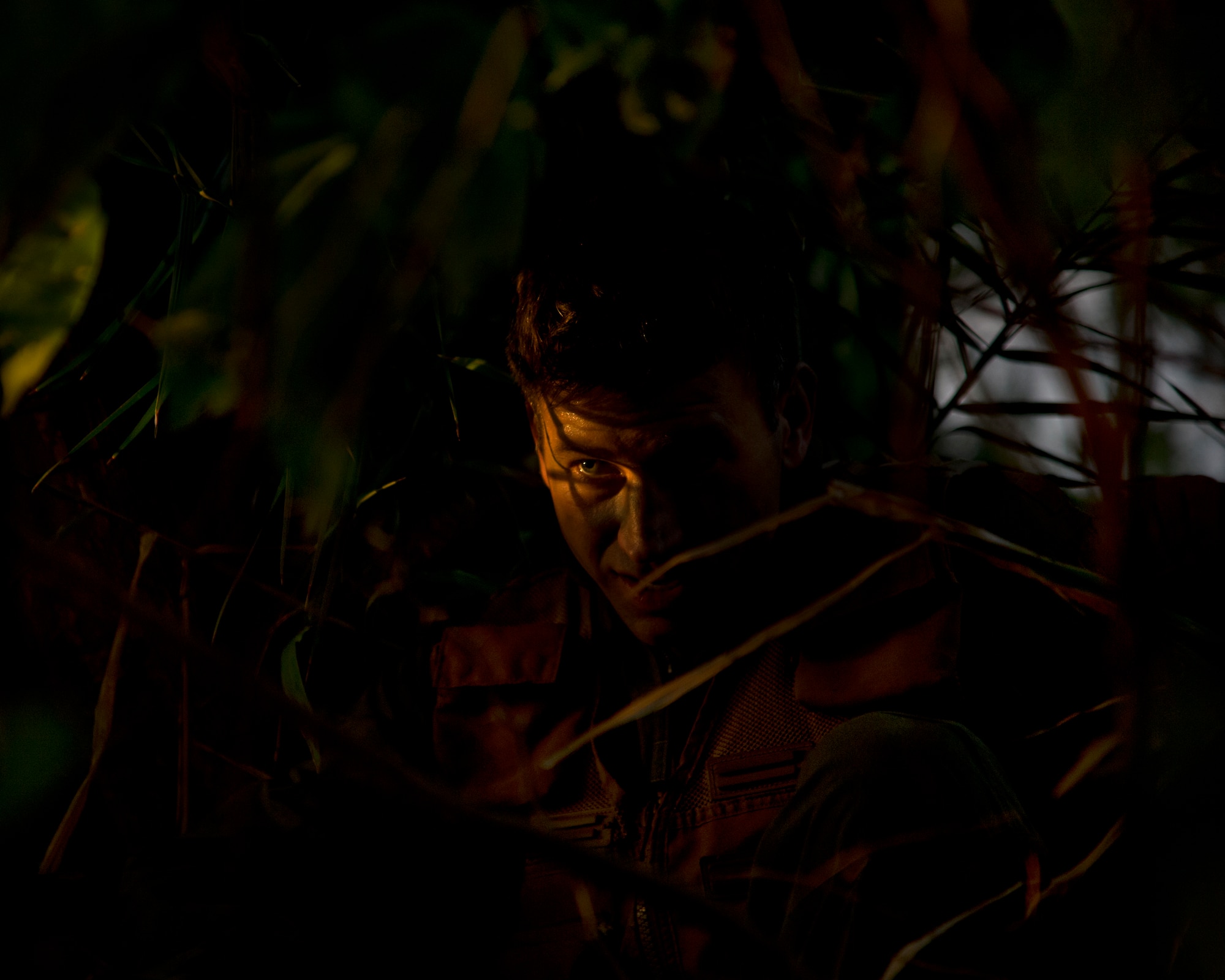 Maj. Dan Allen, a pilot evaluator for the 96th Air Refueling Squadron, takes cover in the brush during combat survival training on Joint Base Pearl Harbor-Hickam, Hawaii, March 26, 2015. Allen led a team of four during four hours of training that is designed to simulate the aircrew going down in a hostile environment. The aircrew uses teamwork to conceal their location, evade opposition forces, and practice proper recovery procedures. (U.S. Air Force photo by Tech. Sgt. Aaron Oelrich/Released)