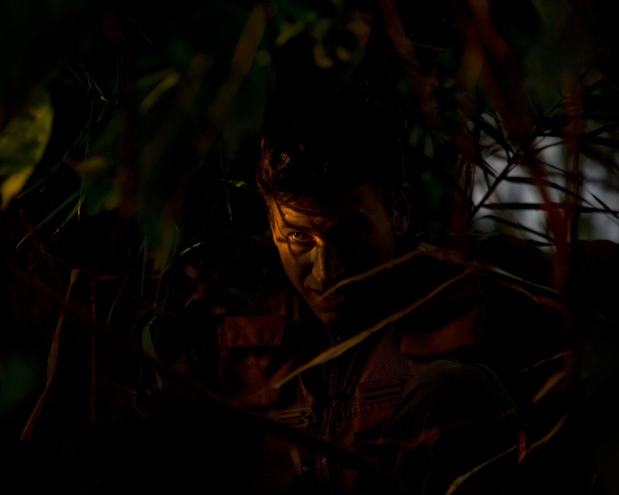 Maj. Dan Allen, a pilot evaluator for the 96th Air Refueling Squadron, takes cover in the brush during combat survival training on Joint Base Pearl Harbor-Hickam, Hawaii, March 26, 2015. Allen led a team of four during four hours of training that is designed to simulate the aircrew going down in a hostile environment. The aircrew uses teamwork to conceal their location, evade opposition forces, and practice proper recovery procedures. (U.S. Air Force photo by Tech. Sgt. Aaron Oelrich/Released)