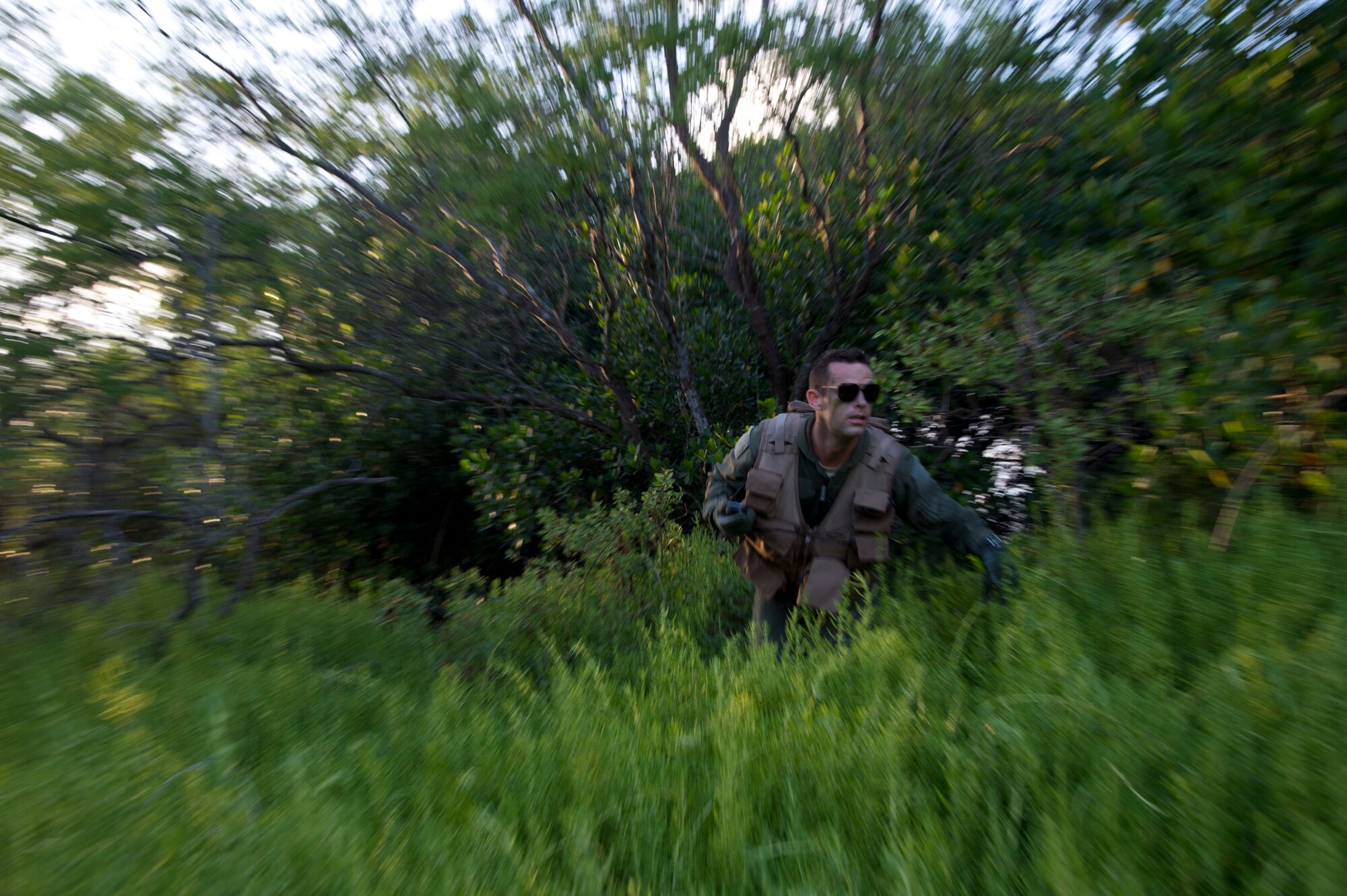 Senior Airman Kenneth Stricker, a boom operator for the 96th Air Refueling Squadron, runs from cover during combat survival training on Joint Base Pearl Harbor-Hickam, Hawaii, March 26, 2015. This training simulates the aircrew going down in a hostile environment. The aircrew uses teamwork to conceal their location, evade opposition forces, and practice proper recovery procedures. (U.S. Air Force photo by Tech. Sgt. Aaron Oelrich/Released)
