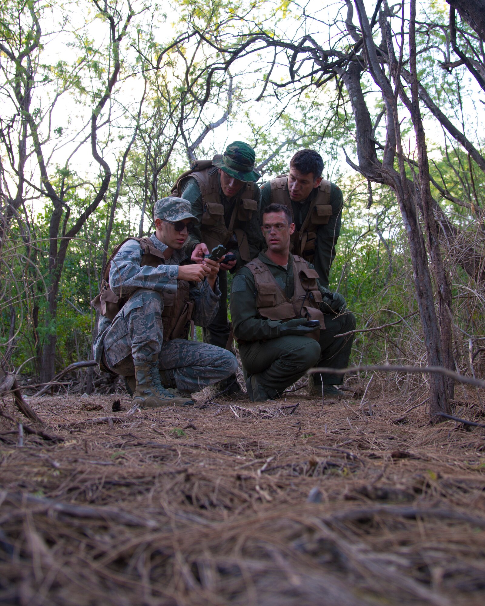 (Bottom left) Senior Airman Scott Willard, a boom operator for the 96th Air Refueling Squadron, (Top left) Capt. Matt Savage, a pilot for the 96th Air Refueling Squadron,(bottom right) Senior Airman Kenneth Stricker, a boom operator for the 96th Air Refueling Squadron, and ( top right) Maj. Dan Allen, a pilot evaluator for the 96th Air Refueling Squadron, stopped to check their quadrants as they navigate to a checkpoint during combat survival training on Joint Base Pearl Harbor-Hickam, Hawaii, March 26, 2015. (U.S. Air Force photo by Tech. Sgt. Aaron Oelrich/Released)