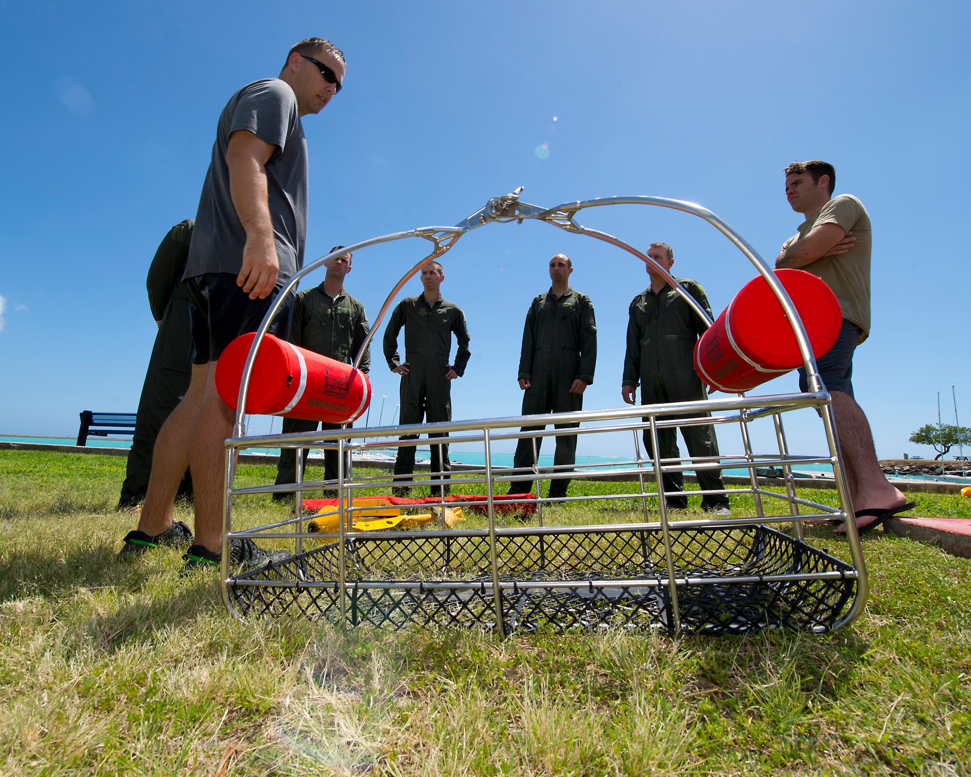 Tech. Sgt. Jeffrey Ray, a Survival Evade Resist and Escape specialist for the 15th Operational Support Squadron explains the different types of recovery devices used for water rescues to Airmen from the 535th Airlift Squadron 65th Airlift Squadron, and the 96th Air Refueling Squadron during water survival training on Joint Base Pearl Harbor-Hickam, Hawaii, March 23, 2015. The water survival training is a triennial requirement for all aircrew to refresh their SERE water survival skills. (U.S. Air Force photo by Tech. Sgt. Aaron Oelrich/Released)  