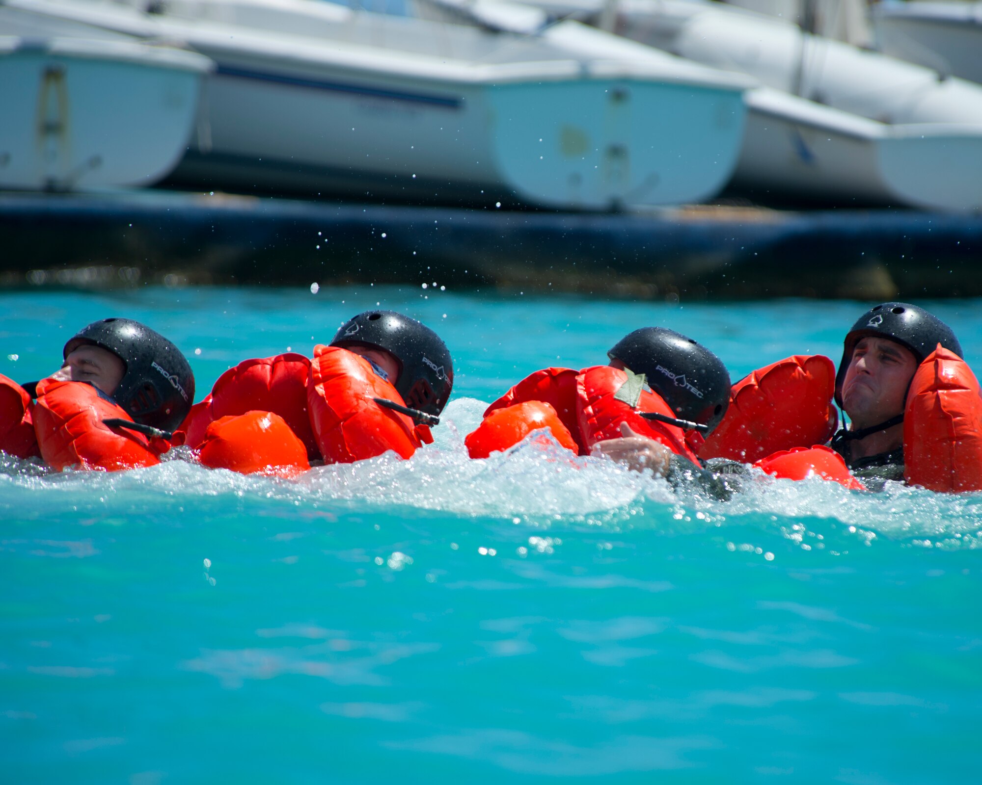 Airmen from the 535th Airlift Squadron, 65th Airlift Squadron and the 96th Air Refueling Squadron, swim as a team during water survival training on Joint Base Pearl Harbor-Hickam, Hawaii, March 23, 2015. Airmen are linked together by wrapping their legs around the person in front, keeping everyone together as they swim to a life raft. This method of swimming together ensures everyone is accounted for and will assist anyone who is injured. (U.S. Air Force photo by Tech. Sgt. Aaron Oelrich/Released) 