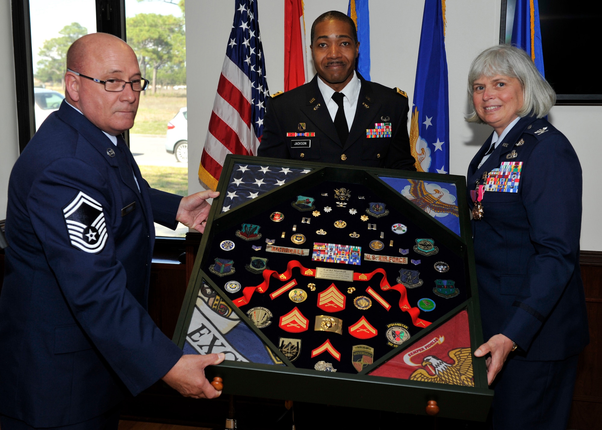 From the Continental U.S. NORAD Region-1st AF (Air Forces Northern)’s Installations & Mission Support Directorate, (A7), Senior Master Sgt. Charles Stoyer IV, Maj. Vincent Jackson and Col. “BJ” Marshall, display the shadow box she received to recognize her retirement following a 34-year military career that included the U.S. Marine Corps. Prior to her retirement, Marshall served as the A7 Director. (U.S. Air Force photo by Airman 1st Class Sergio Gamboa/Released)