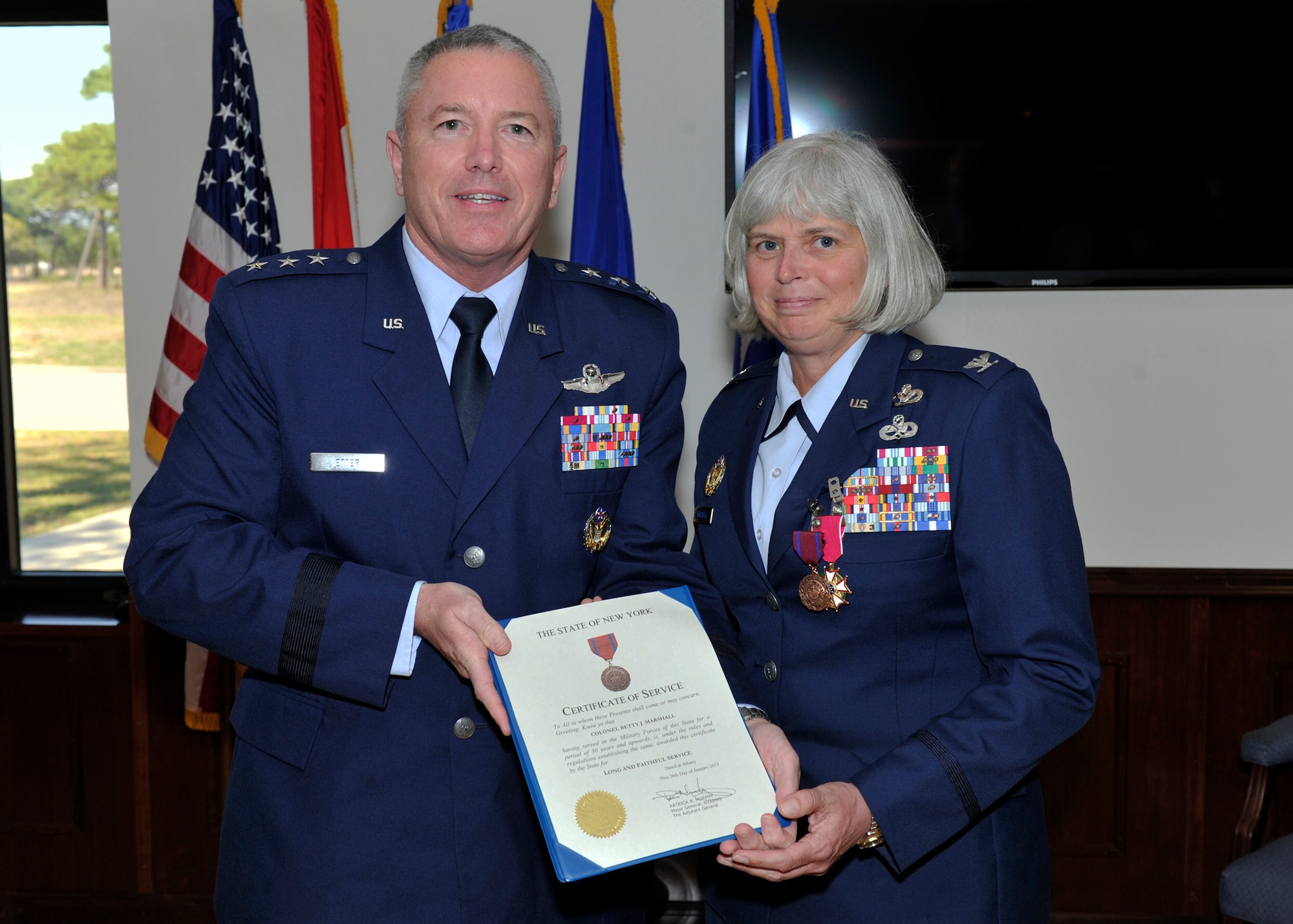 Lt. Gen William Etter, Continental U.S. NORAD Region-1st Air Force (Air Forces Northern) commander, presents Col. “BJ” Marshall, previously Director of Installations and Mission Support for CONR-1st AF (AFNORTH), with her Certificate of Service from the State of New York during her retirement ceremony March 27 after a 34-year career. Marshall began her career as an enlisted Marine in 1981 as a “plane captain,” the person responsible for routine military aircraft care and maintenance. (Air Force photo by Airman 1st Class Sergio Gamboa/Released)