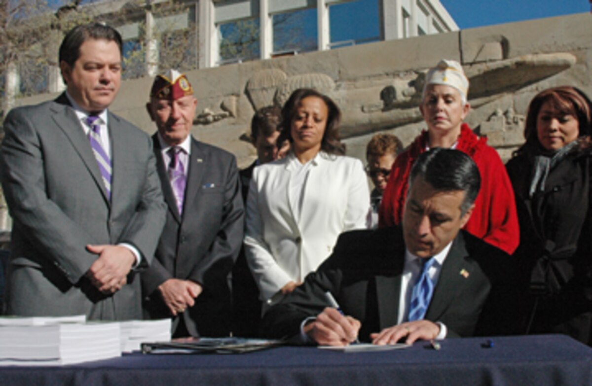 Nevada Gov. Brian Sandoval signs Assembly Bill 76 into law Thursday during the annual Veterans and Military Day at the Legislature here at the Nevada Capitol. The law extends the length of time a Veteran with an honorable discharge can receive a tuition waiver from a Nevada state higher-education school from two to five years.Photo by Sgt. 1st Class Erick Studenicka, NV ARNG (released)
