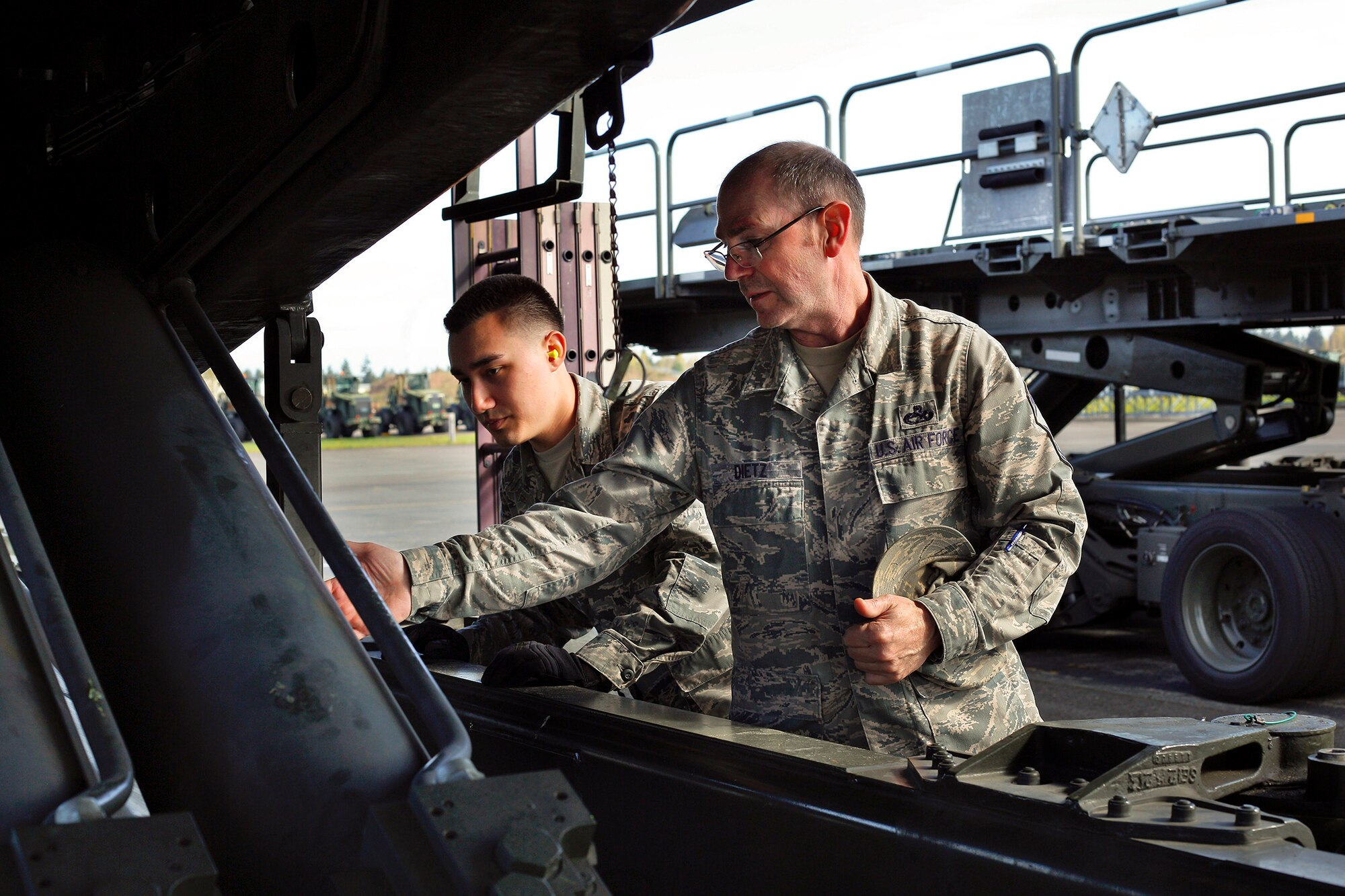 Chief Master Sgt. Christopher Dietz, 86th Aerial Port Squadron Air Transportation superintendent, Joint Base Lewis-McChord, Washington, demonstrates a pre-vehicle check on a 60K pallet loader for Airman 1st Class Will Akers, one the squadron's newest cargo specialists, March 27, 2015. Both the 86th and 36th Aerial Port Squadrons are in need of air transportation specialists. Dietz said in his squadron there are positions available all the way to the rank of master sergeant. (U.S. Air Force Reserve photo by Jake Chappelle)