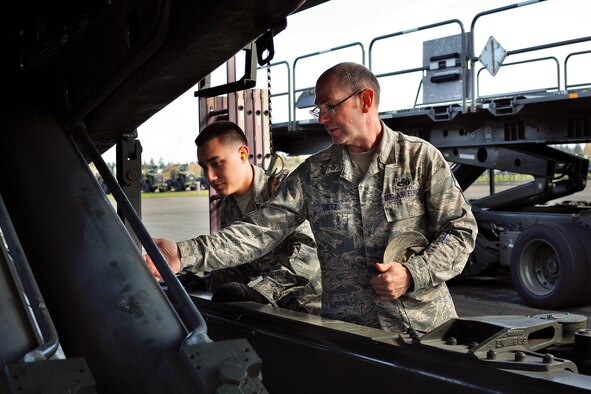 Chief Master Sgt. Christopher Dietz, 86th Aerial Port Squadron Air Transportation superintendent, Joint Base Lewis-McChord, Washington, demonstrates a pre-vehicle check on a 60K pallet loader for Airman 1st Class Will Akers, one the squadron's newest cargo specialists, March 27, 2015. Both the 86th and 36th Aerial Port Squadrons are in need of air transportation specialists. Dietz said in his squadron there are positions available all the way to the rank of master sergeant. (U.S. Air Force Reserve photo by Jake Chappelle)