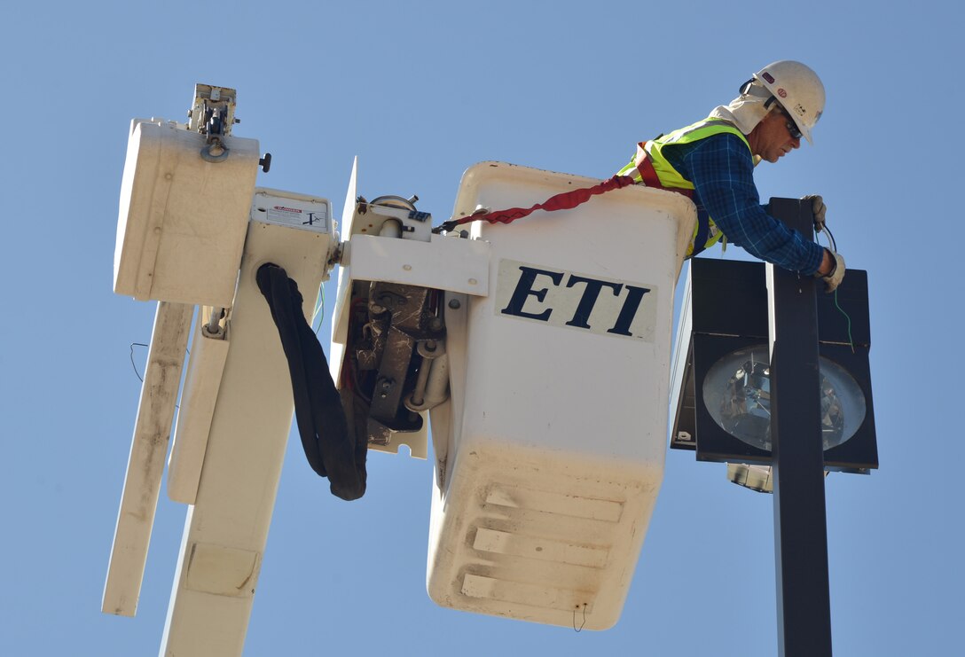 Steve Thacker, an electrician from B&D Industries Albuquerque, replaces street  and parking lot halide lights with new energy efficient LED lights. About 470 lights on the east side of the base will be switched, saving the base about $77,000 a year in energy and replacement costs. (Photo by Todd Berenger)