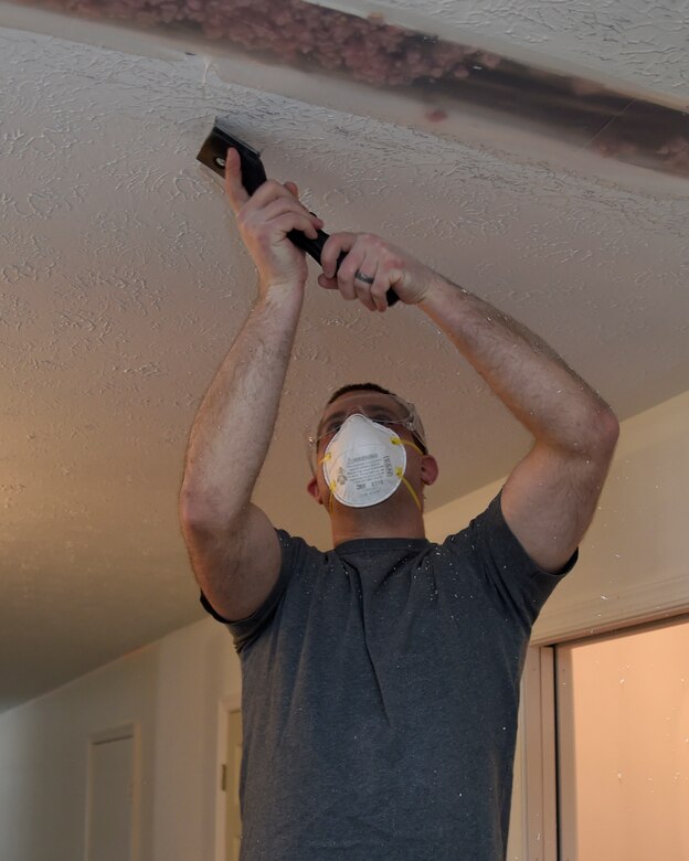 Senior Airman Tyler Ketelhut, an 89th Communications Squadron Power Pro technician, scrapes the ceiling of a home in Bowie, Md., Jan. 29, 2015. The house belongs to Tech. Sgt. Melvin Mateo, an 89th Communications Squadron Government Network Operations Center crew chief. The home is being renovated to meet requirements of his special-needs daughter. (U.S. Air Force photo/Airman 1st Class Ryan J. Sonnier)