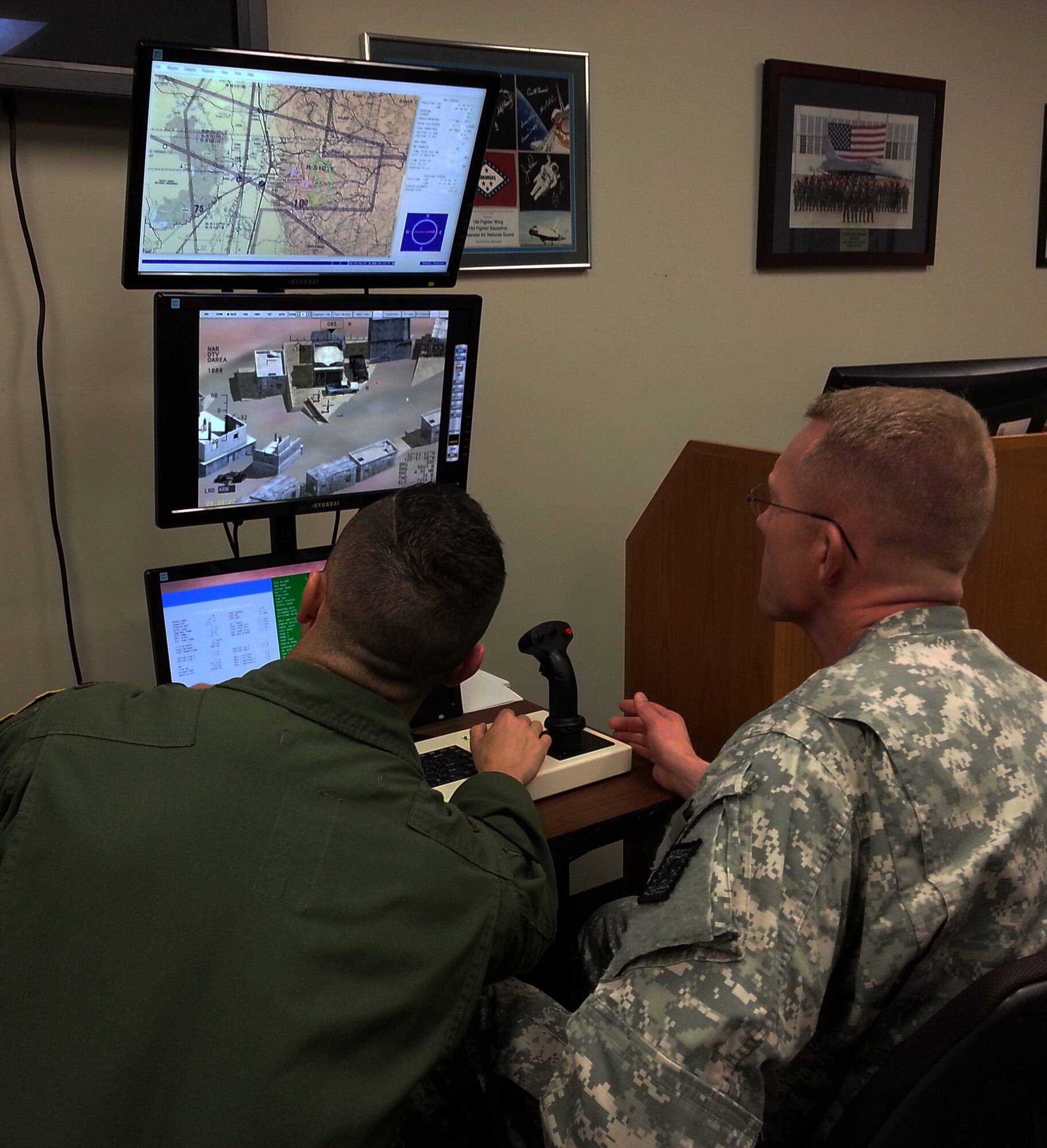 Lt. Col. Joel Lynch, Arkansas National Guard state public affairs officer, right, receives a briefing on the Predator Reaper Integrated Mission Environment system from a pilot with the 184th Attack Squadron at Ebbing Air National Guard Base, Fort Smith, Ark., March 25, 2015. (U.S. Air National Guard photo by Maj. Heath Allen/released)