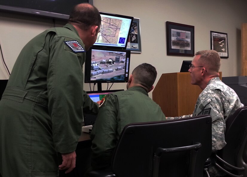 Lt. Col. Joel Lynch, Arkansas National Guard state public affairs officer, right, receives a briefing on the Predator Reaper Integrated Mission Environment system from a pilot and sensor operator with the 184th Attack Squadron at Ebbing Air National Guard Base, Fort Smith, Ark., March 25, 2015. (U.S. Air National Guard photo by Maj. Heath Allen/released)