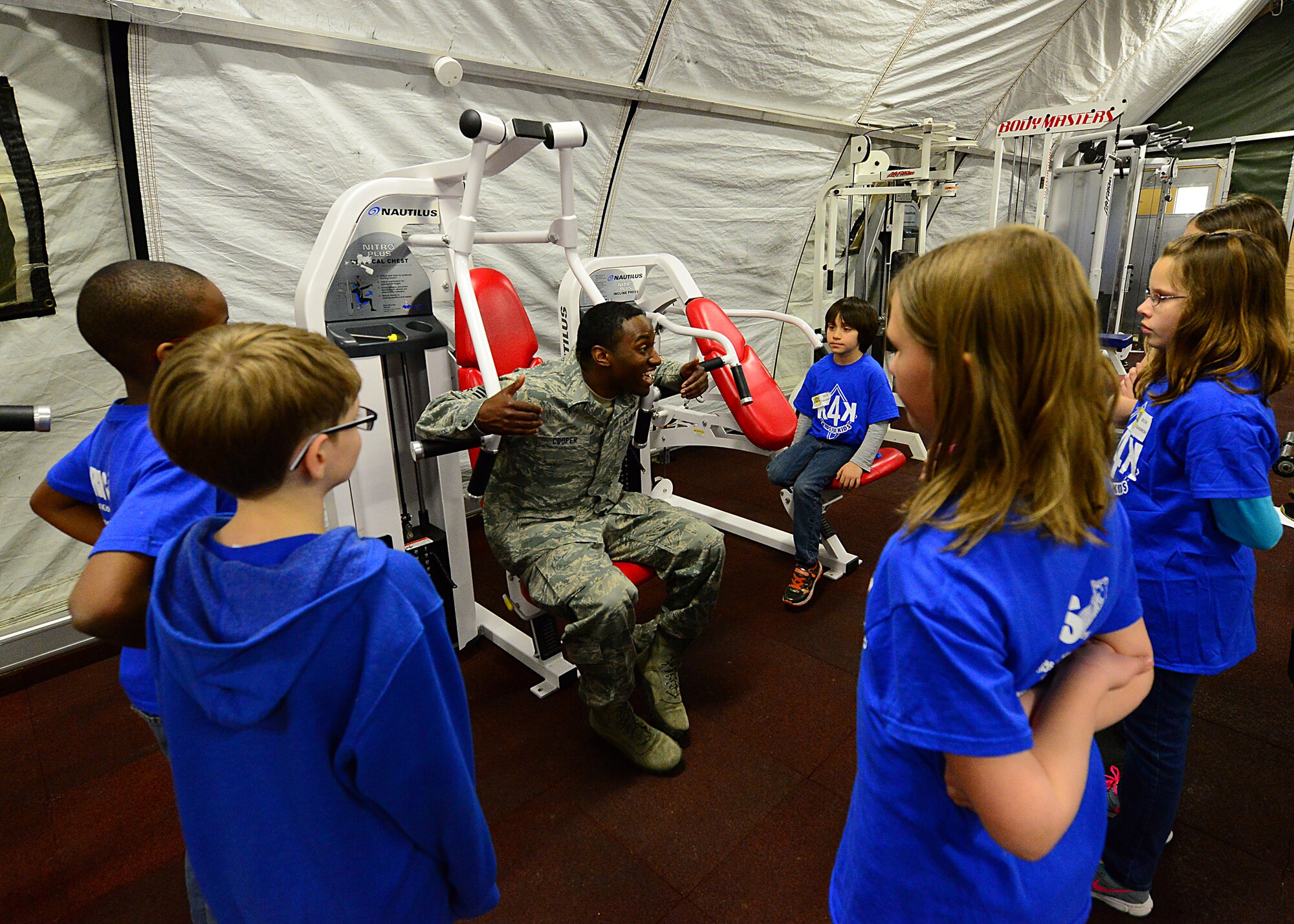 Staff Sgt. Terry Cooper, 435th Construction and Training Squadron, services contingency instructor teaches Ramstien Intermediate School students how to properly use fitness equipment during a mock pre-deployment line held on the 435th Air Ground and Operations Wing, 435th Construction and Training Squadron’s silver flag compound, March 27, 2015.  Ramstein units came together and gave RIS students the opportunity to deploy like their Airmen and Soldier parents. (U.S. Air Force photo/Tech. Sgt. Daylena S. Ricks)
