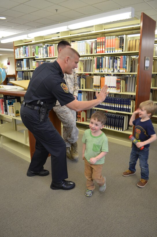 Deputy Police Chief Joseph Riley reads trades high fives with children during the base library’s story hour on March 17. Security Battalion will send police officers and firefighters to the event about once per month from now on as part of a community outreach effort.