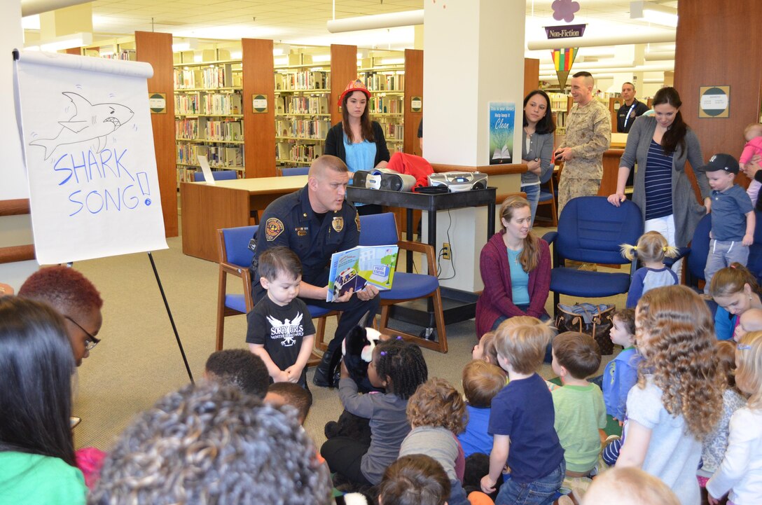 Deputy Police Chief Joseph Riley reads a story to children during the base library’s story hour on March 17. Security Battalion will send police officers and firefighters to the event about once per month from now on as part of a community outreach effort.